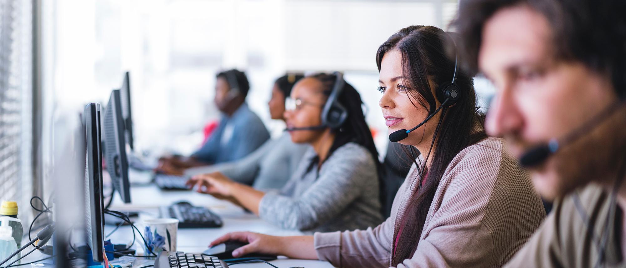 People wearing headphones and sitting inside a call center