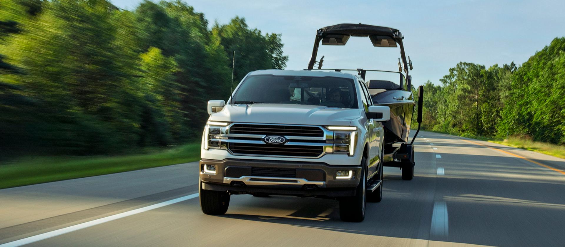 2027 Ford F-150® Lariat® model pulling a boat on a two lane road