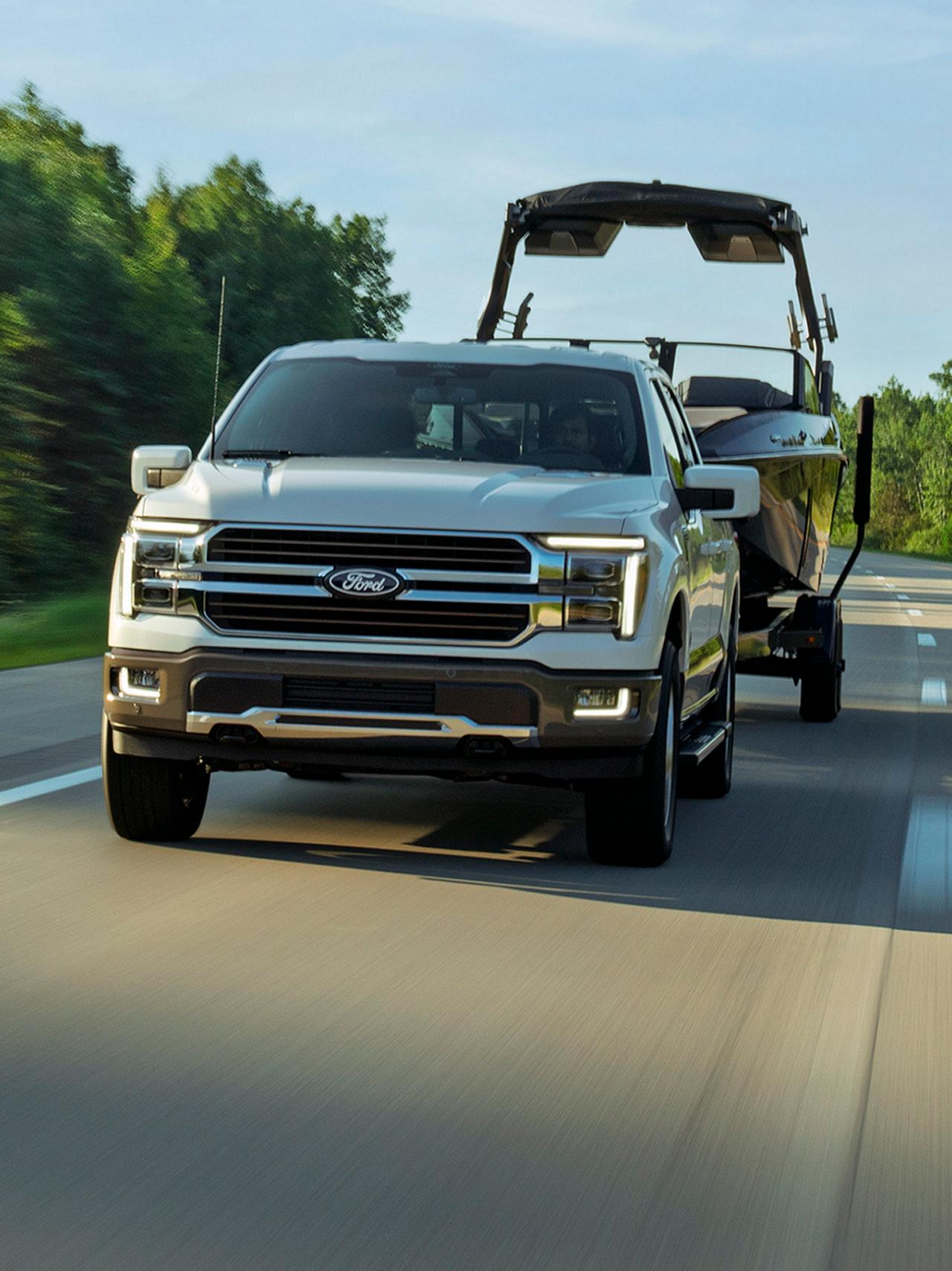 A 2027 Ford F-150® Lariat® pickup pulling a boat on a highway