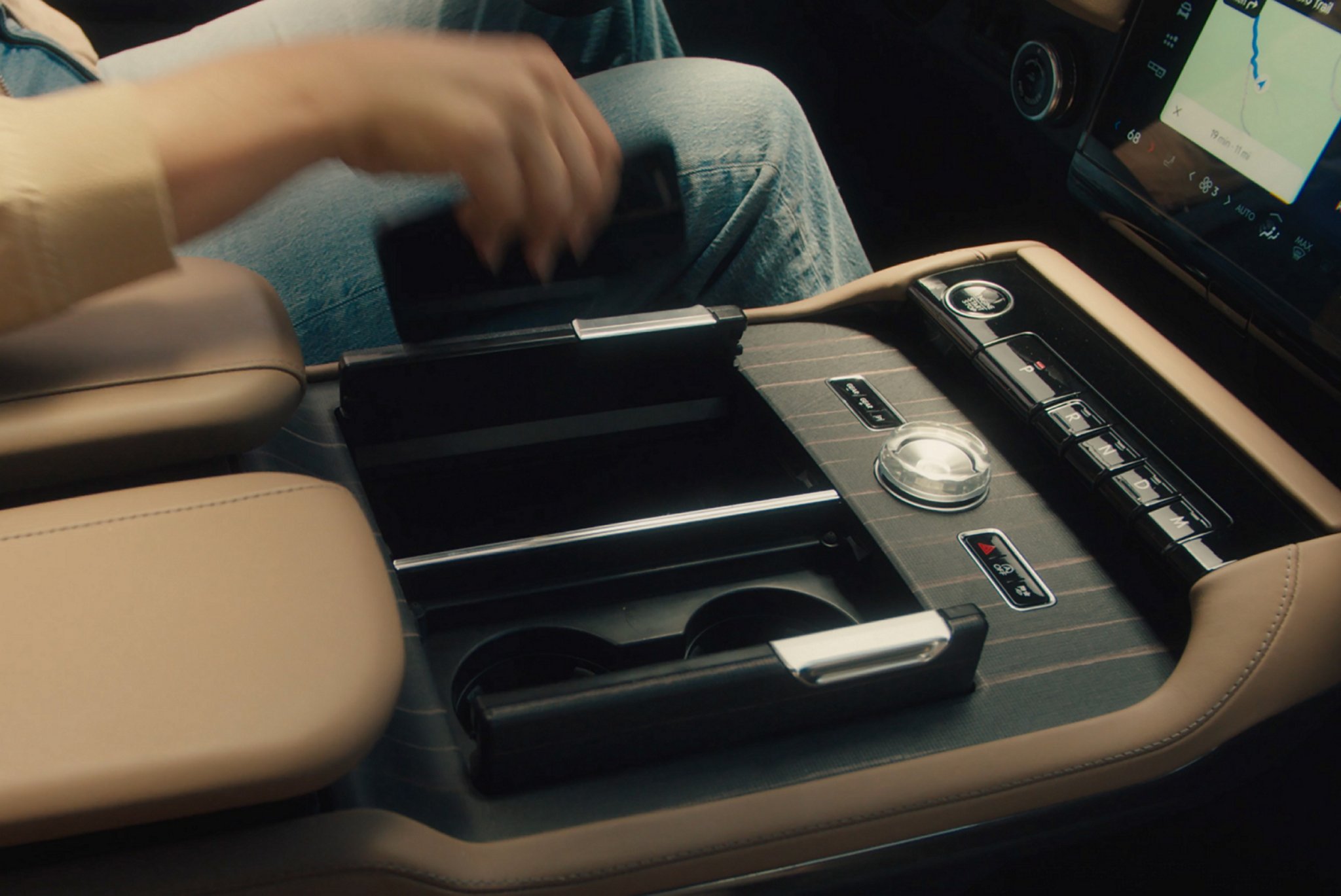 Le conducteur d’un Lincoln Black Label Navigator® 2025 s’étend pour placer un téléphone intelligent sur le tapis de recharge sans fil