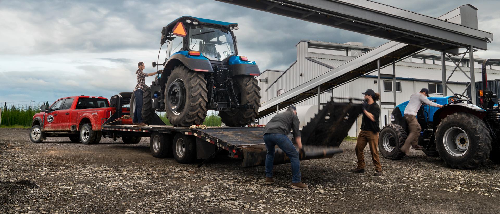 2026 Ford Super Duty® F-450® XL model in Race Red pulling a trailer with a heavy tractor on it
