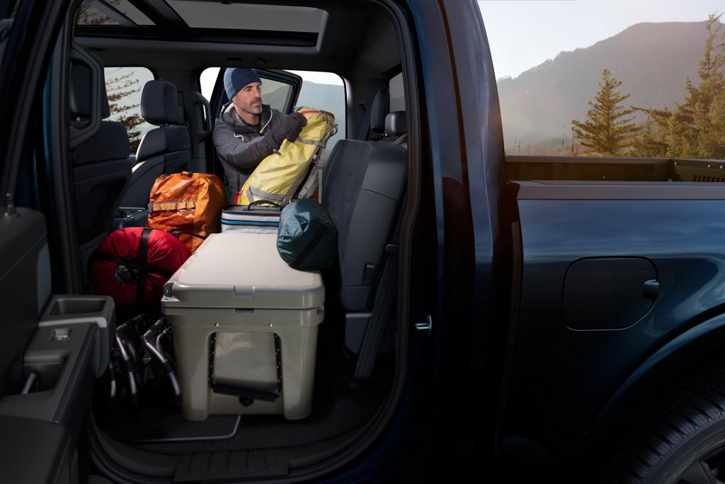 Hombre cargando equipos dentro de una camioneta Ford F-150® 2026 resaltando los asientos abatibles