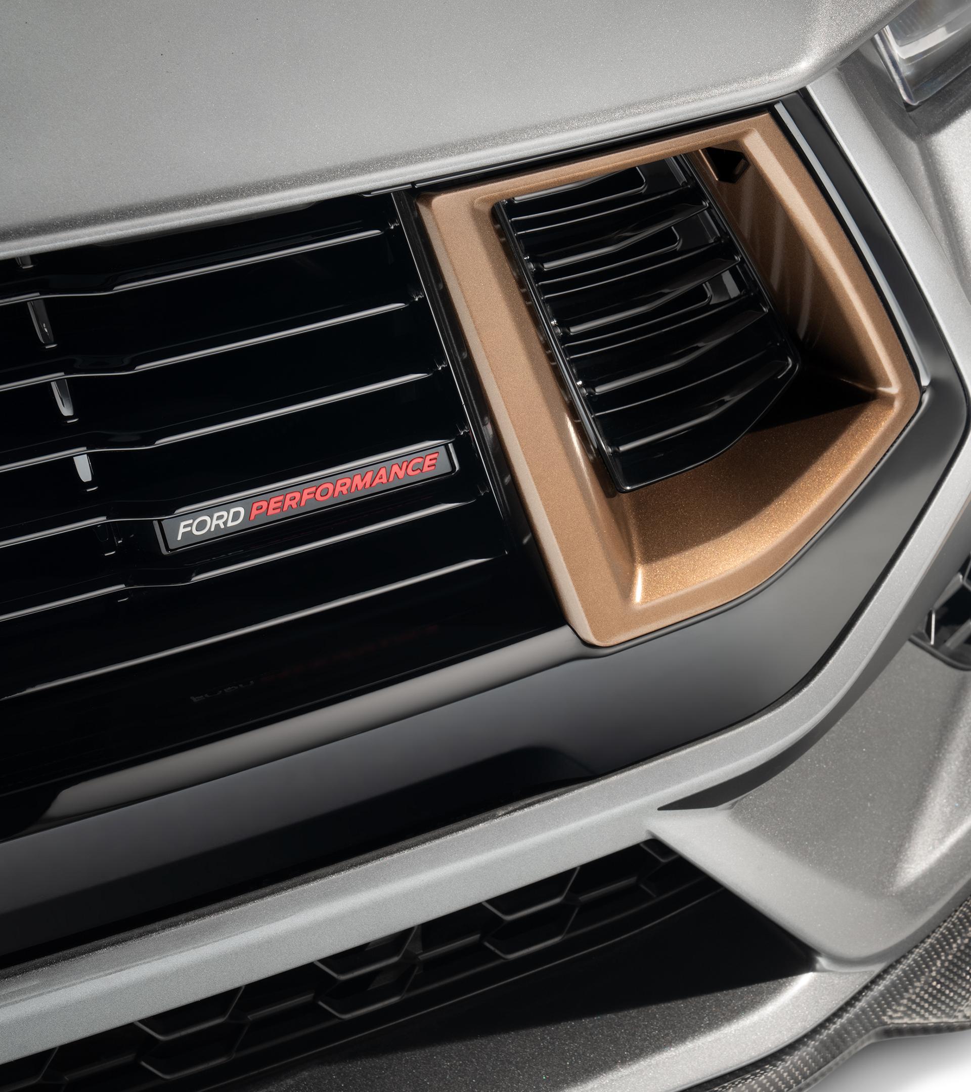 Front-end detail of the unique modular grille with gloss black inserts and a bronze surround, above the carbon-look front splitter