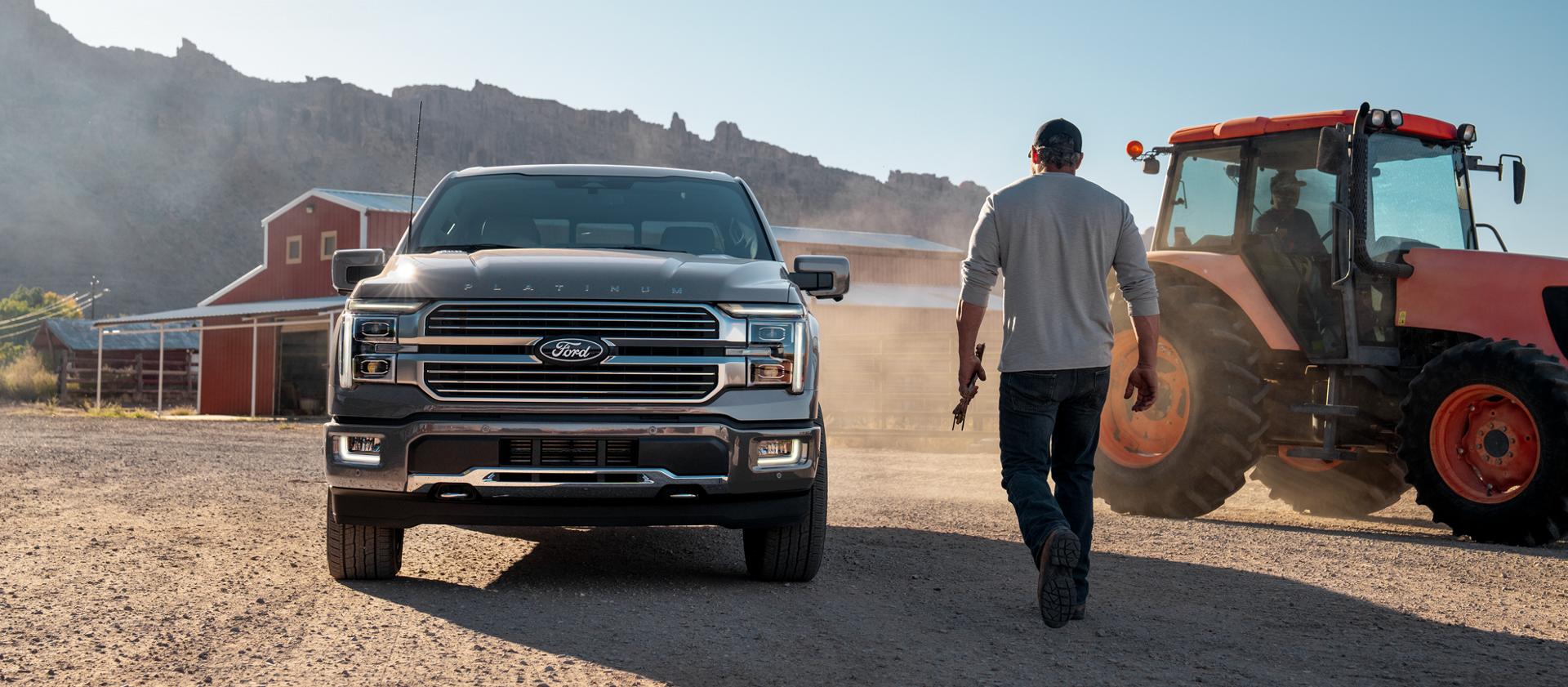 Man walking toward a 2026 Ford F-150® Platinum® model parked near farm equipment