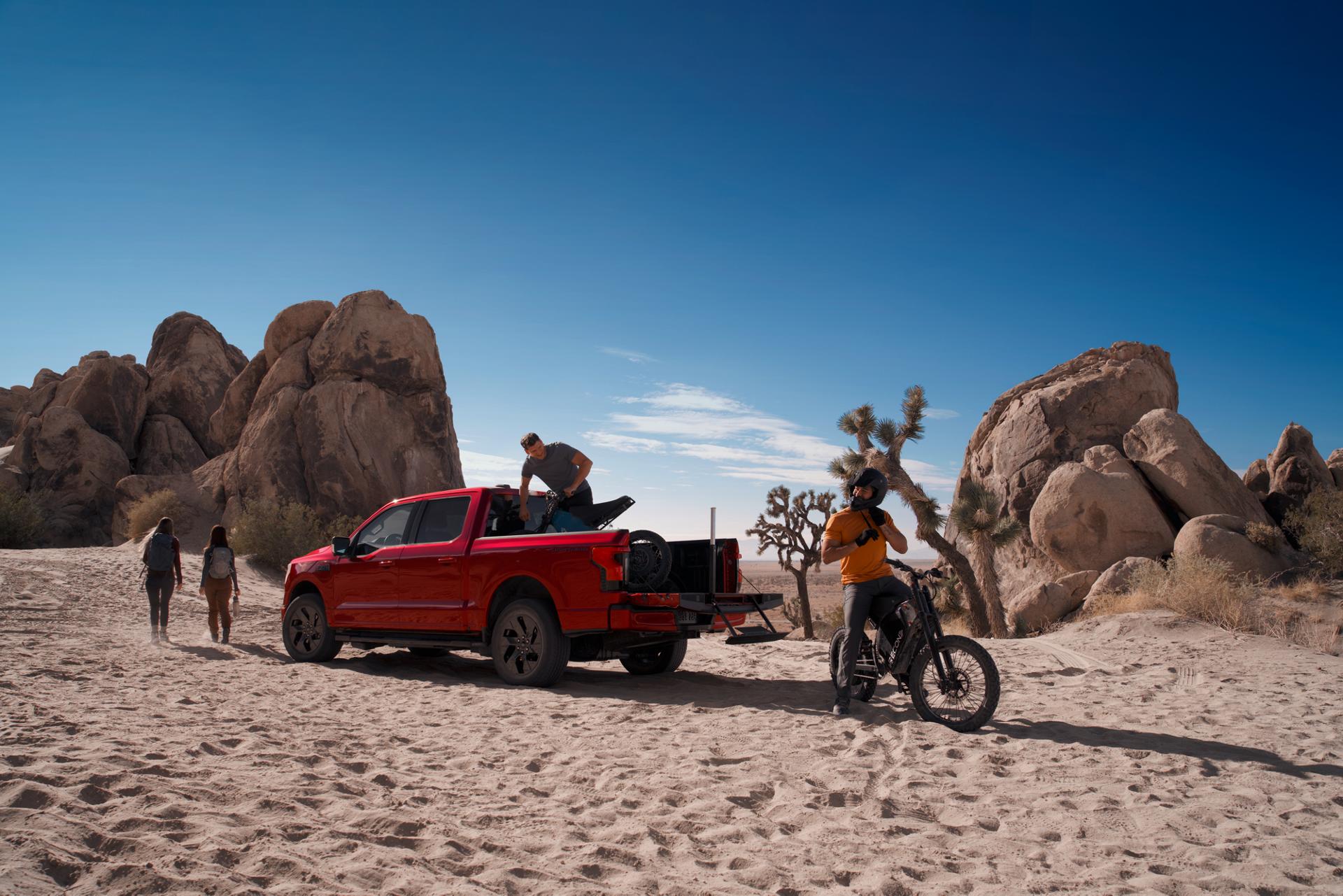 2025 Ford F-150® Lightning® pickup in the desert, with a dirtbike in the bed and one already unloaded