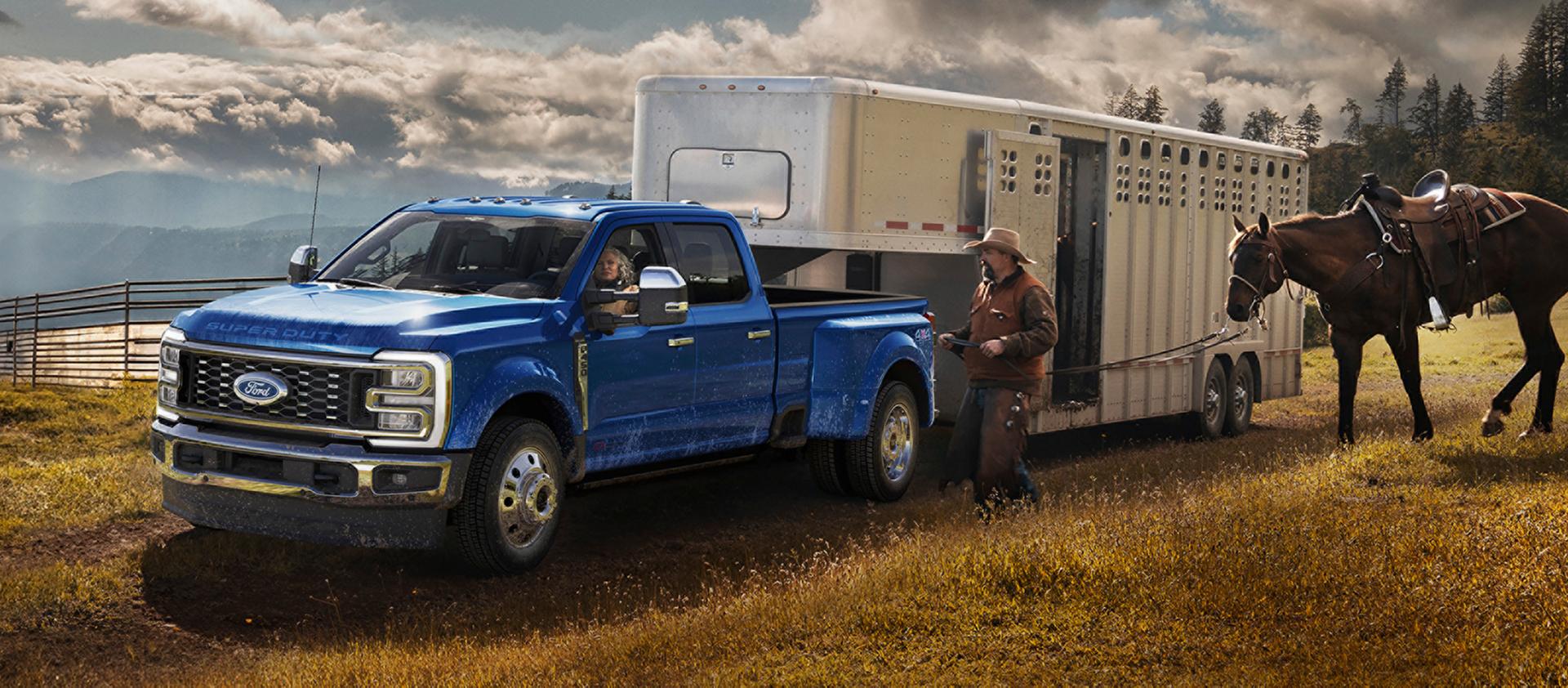 2027 Ford Super Duty® F-450® King Ranch® pickup in Argon Blue towing a horse carrier on a grassy farm