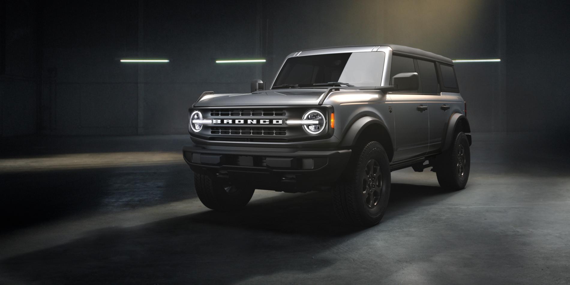 A silver 2025 Ford Bronco Big Bend sitting in a warehouse environment with dramatic lighting