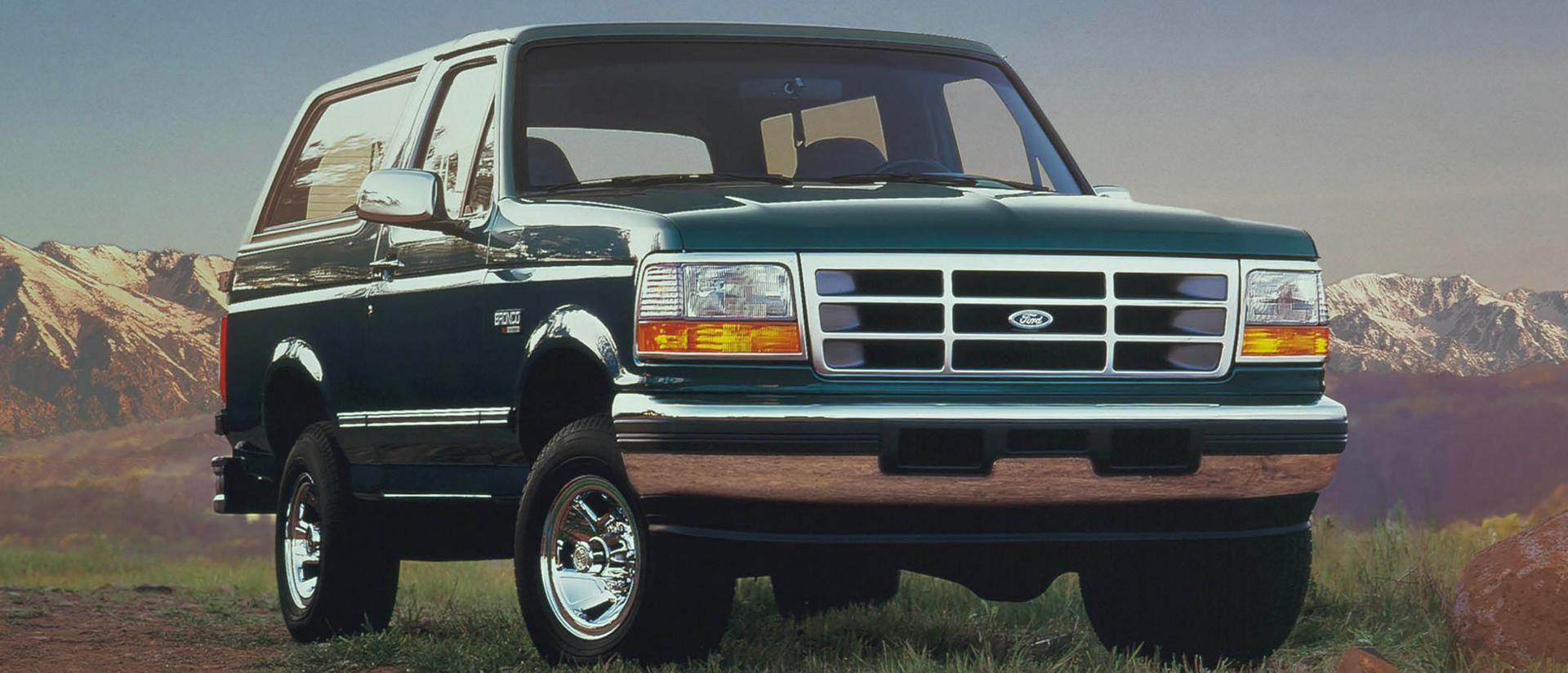 A vintage green 1996 Ford Bronco® model parked in front of a mountain landscape