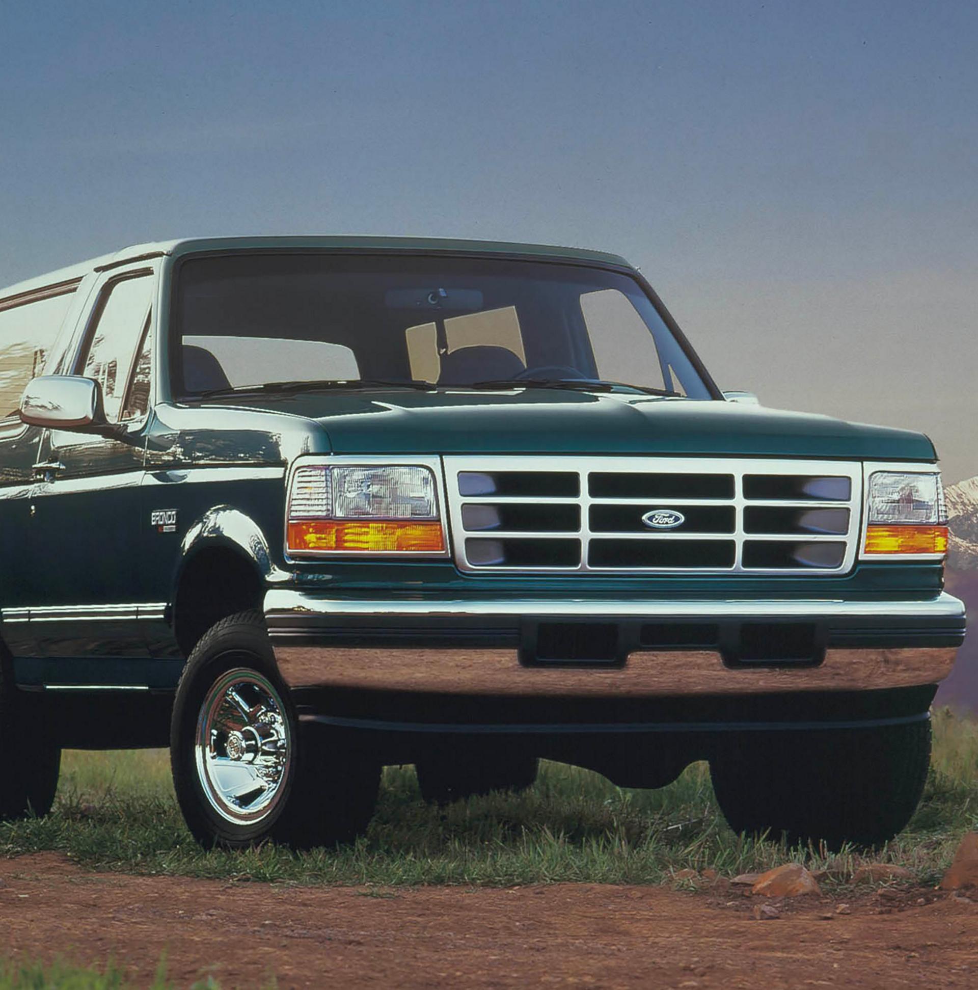 A vintage green 1996 Ford Bronco® model parked in front of a mountain landscape