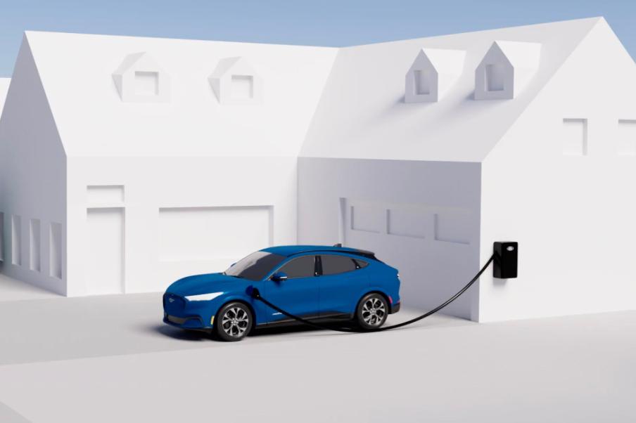 Rendering of a blue Ford Mustang Mach-E® SUV parked in a driveway and connected to a wall-mounted home charging station