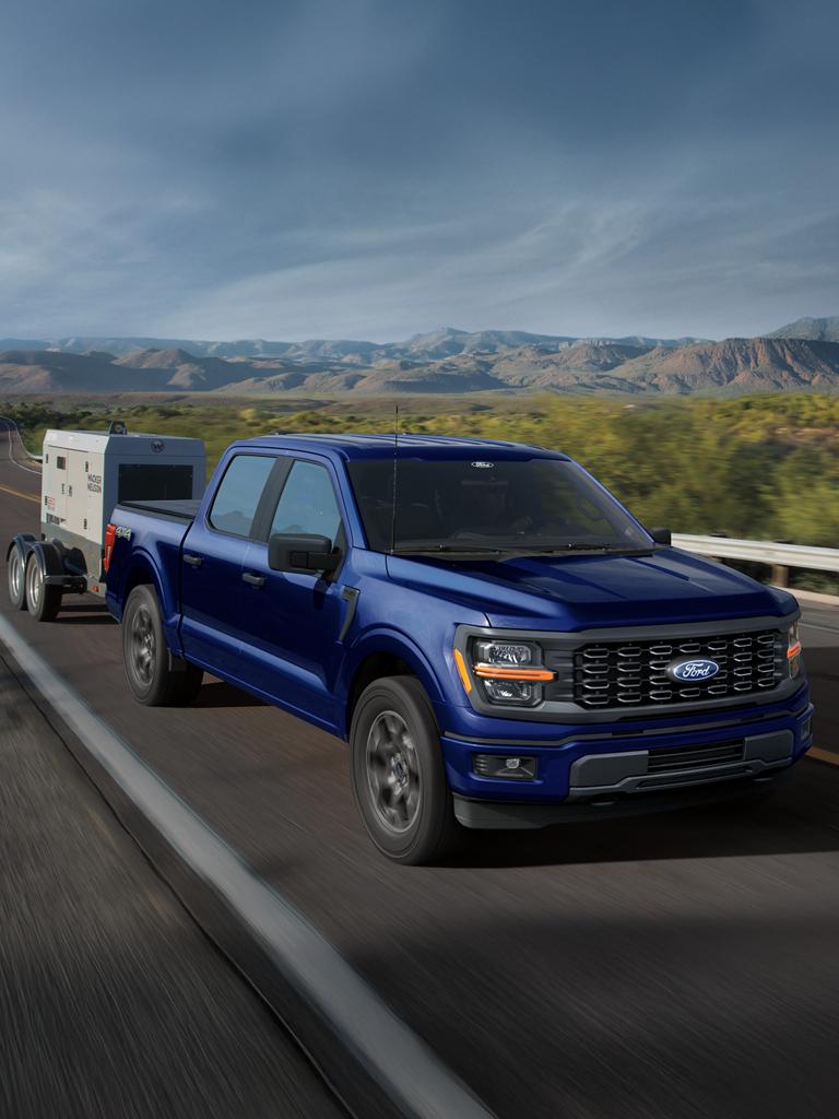 2026 Ford F-150® XL model in Atlas Blue Metallic pulling a small trailer