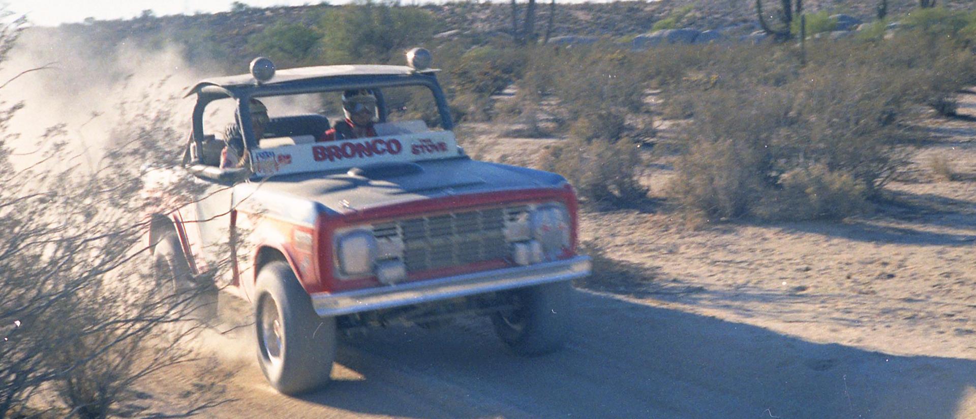 A 1970 Ford Bronco® Racing model pictured tearing across a desert terrain