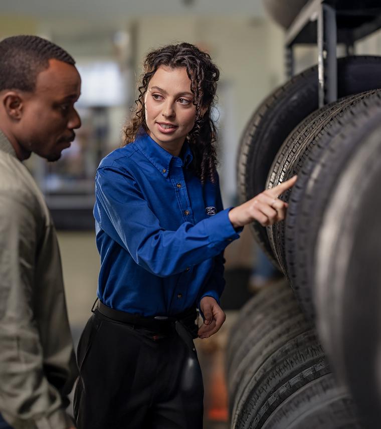 A Ford employee is showing a customer the tire selection