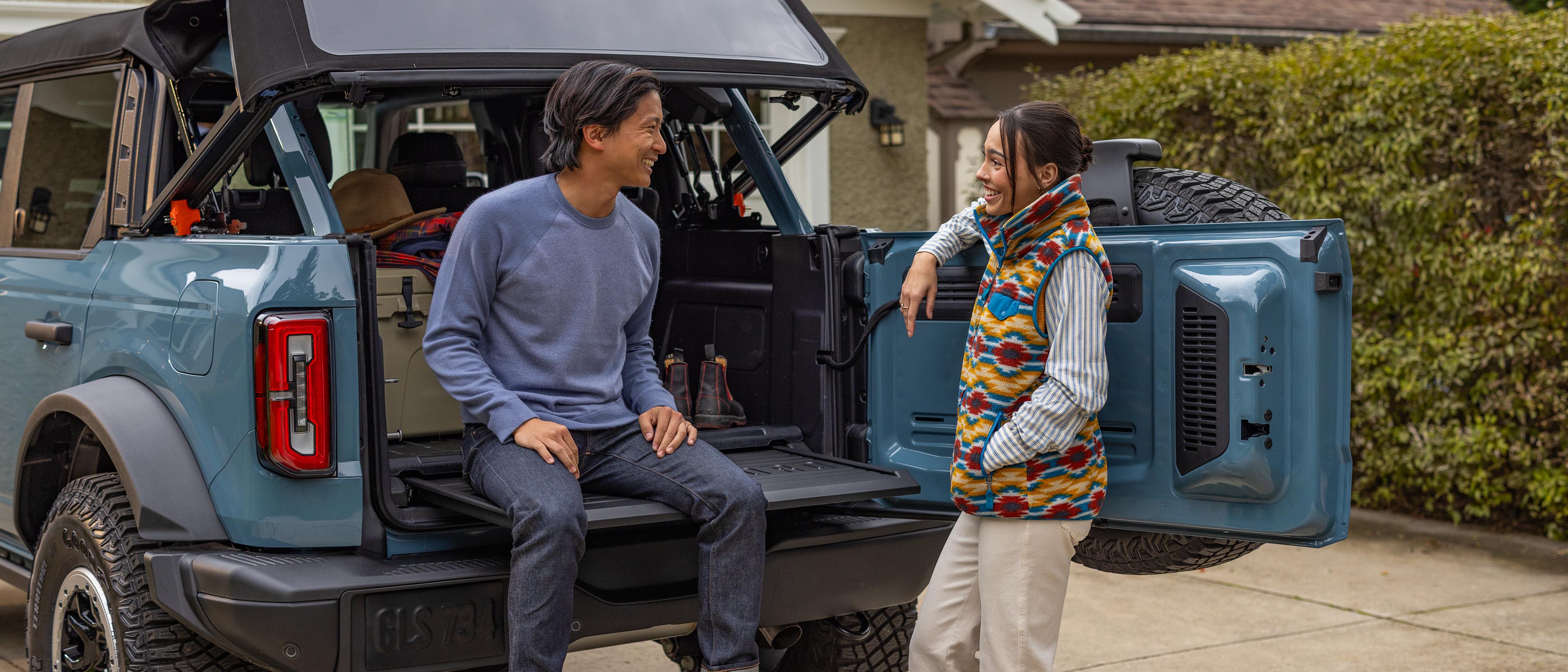 Two friends share a laugh while tailgating with their Ford Bronco® SUV