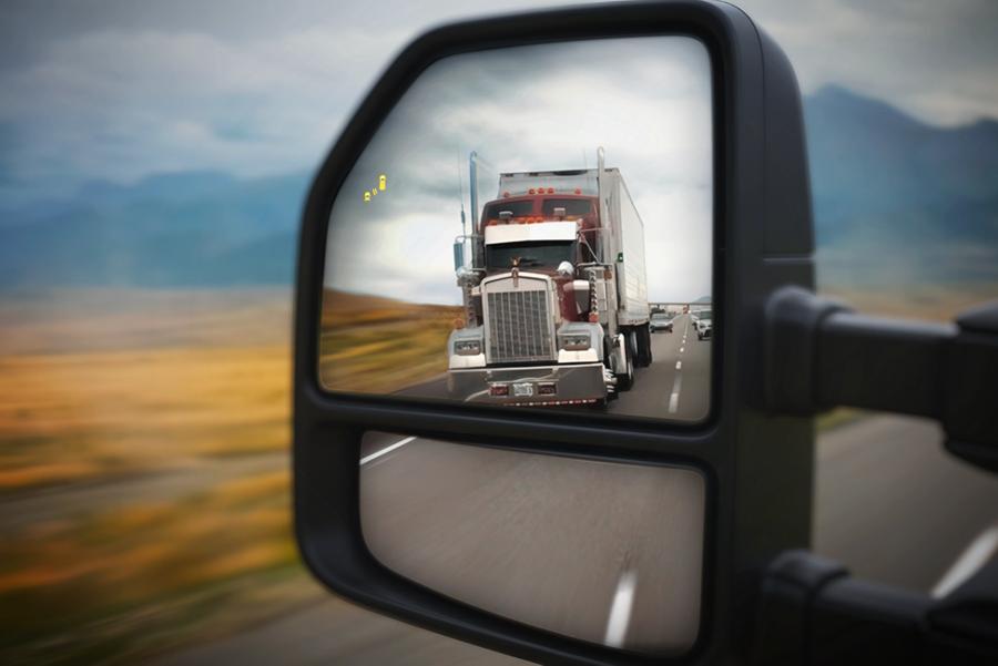 Gros plan du rétroviseur latéral montrant une semi-remorque dans le reflet et l’icône d’alerte BLIS®