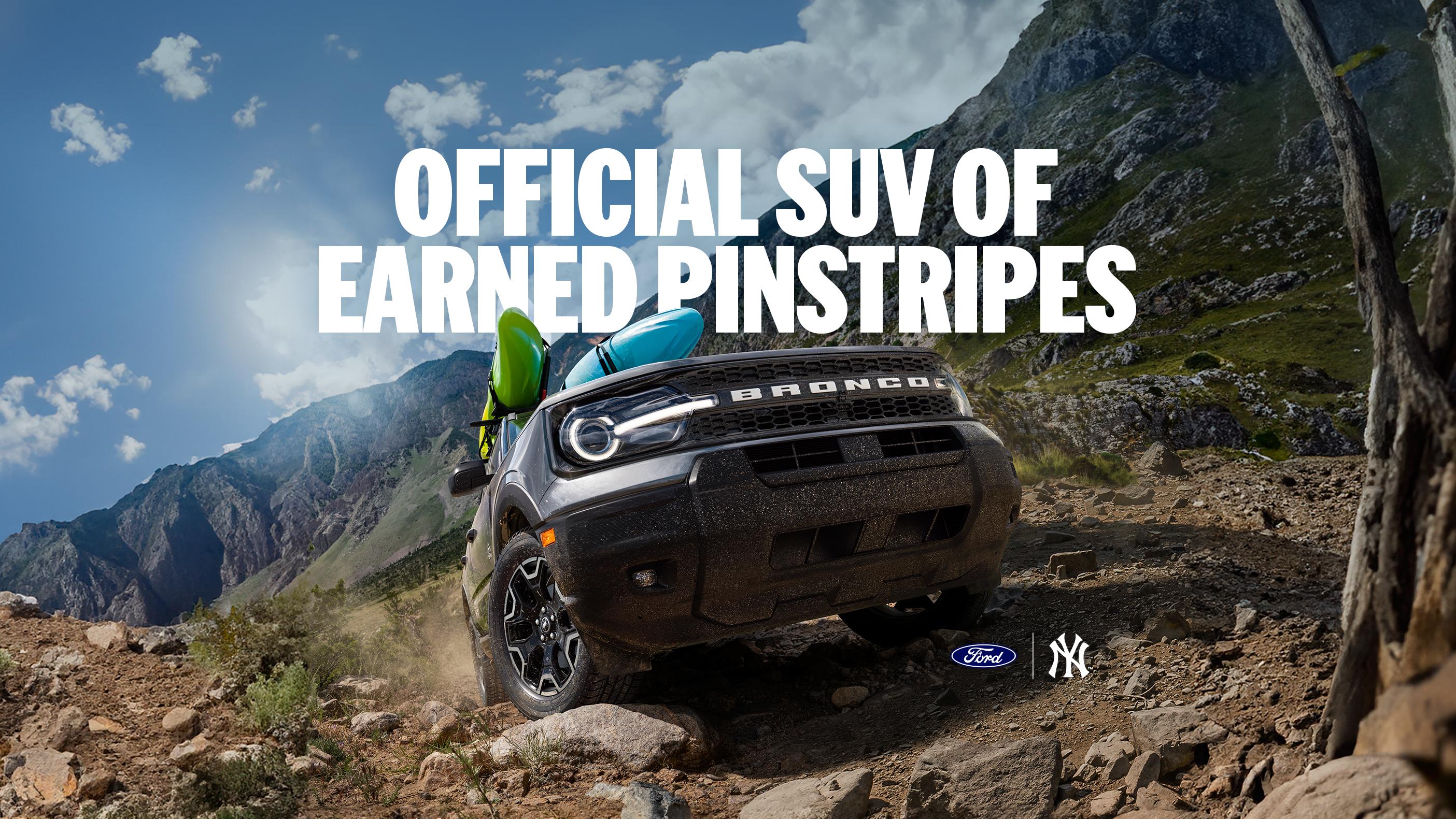 A blue Ford Bronco Sport® SUV is being driven up a hill. Water sport accessories are affixed to the roof rack.