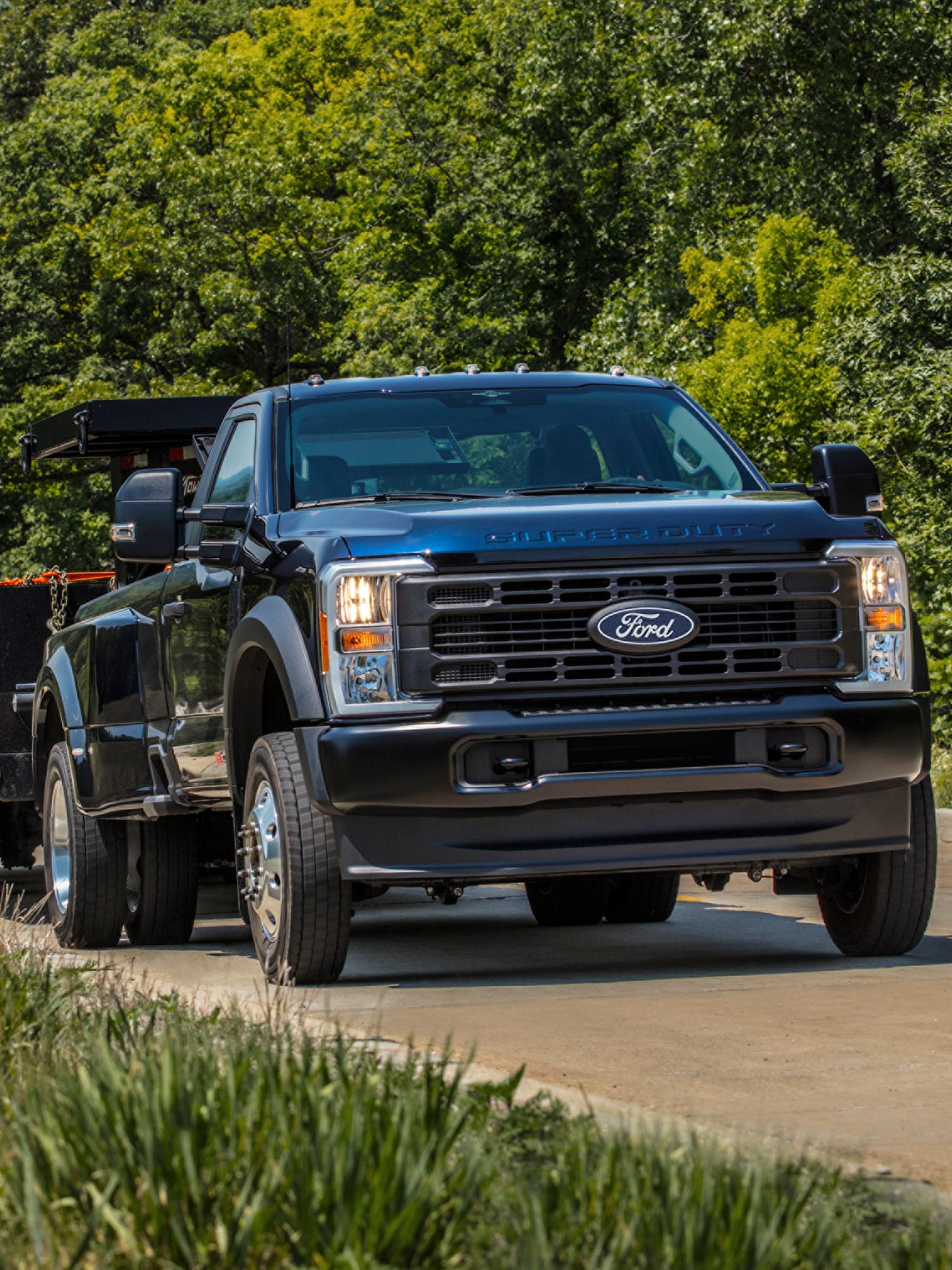 2027 Ford Super Duty® pickup pulling a large flat bed trailer up a paved hill