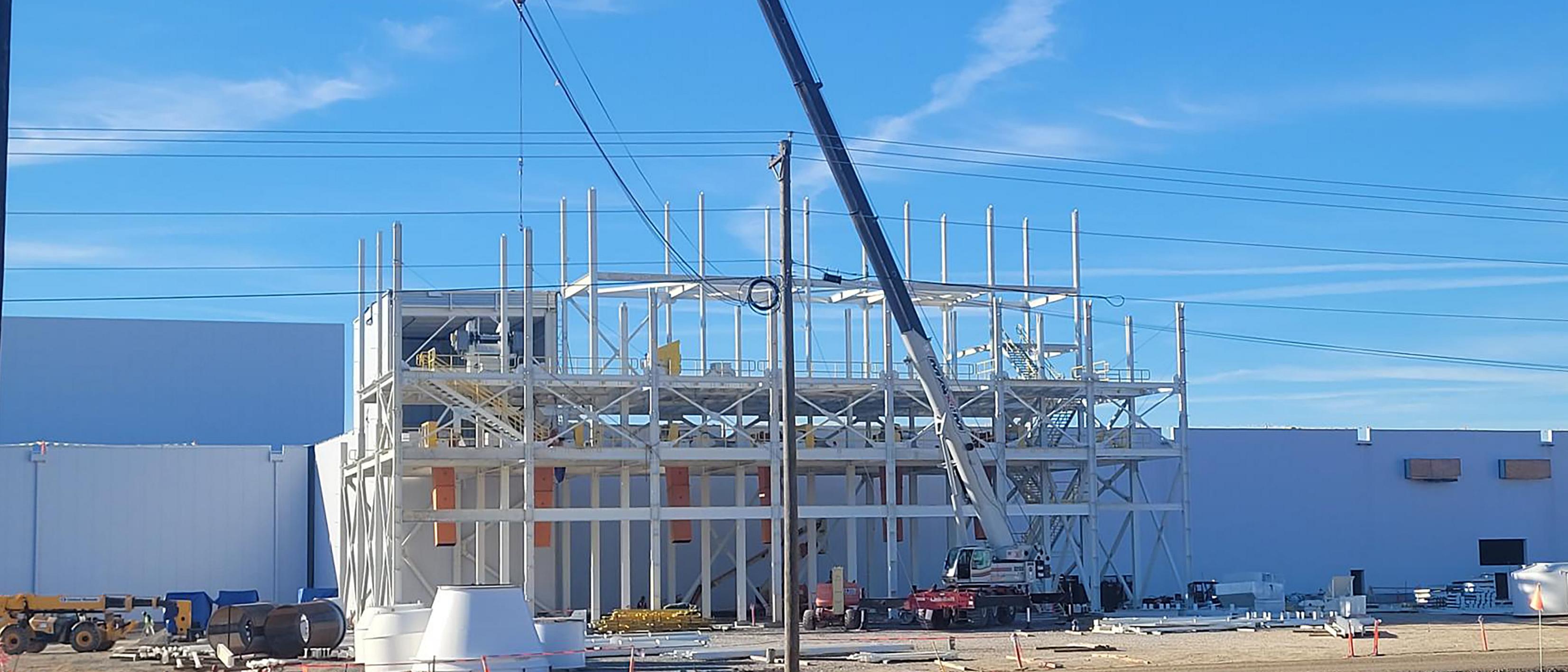 A crane lifts beams at the BlueOval City construction site