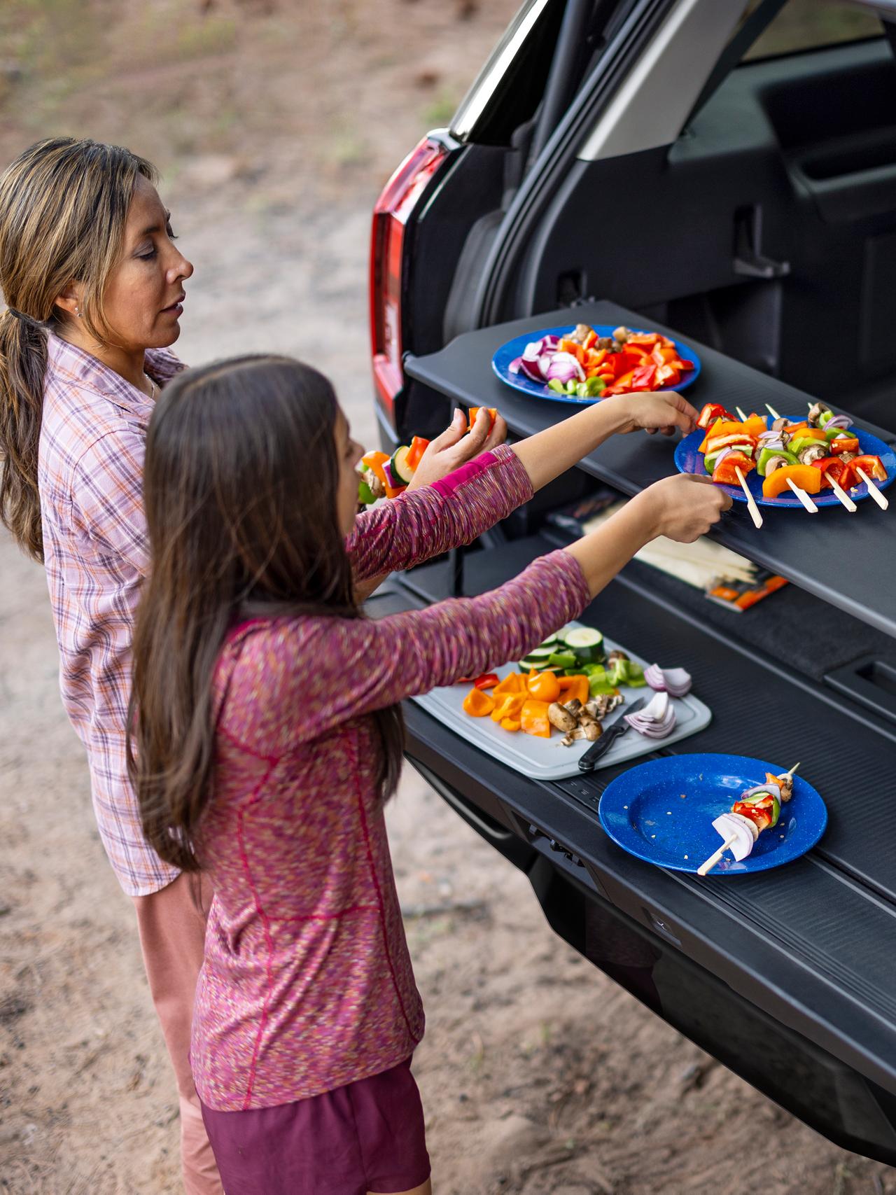 Two people using the available Cargo Tailgate Manager shelf in a parked 2027 Ford Expedition® SUV
