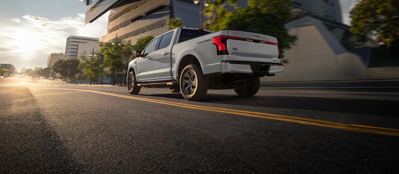 2025 Ford F-150 Lightning driving down road through city