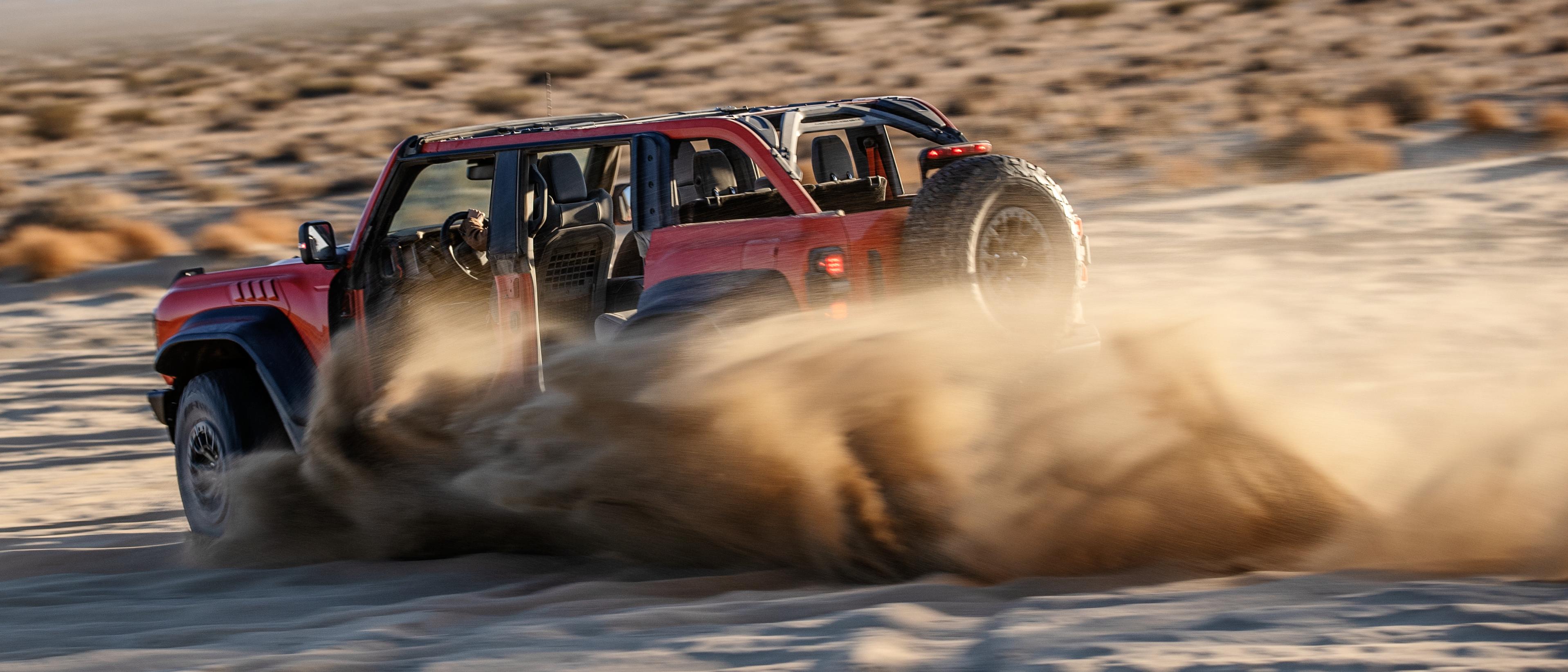 A Bronco Raptor kicks up sand while off-roading in the desert