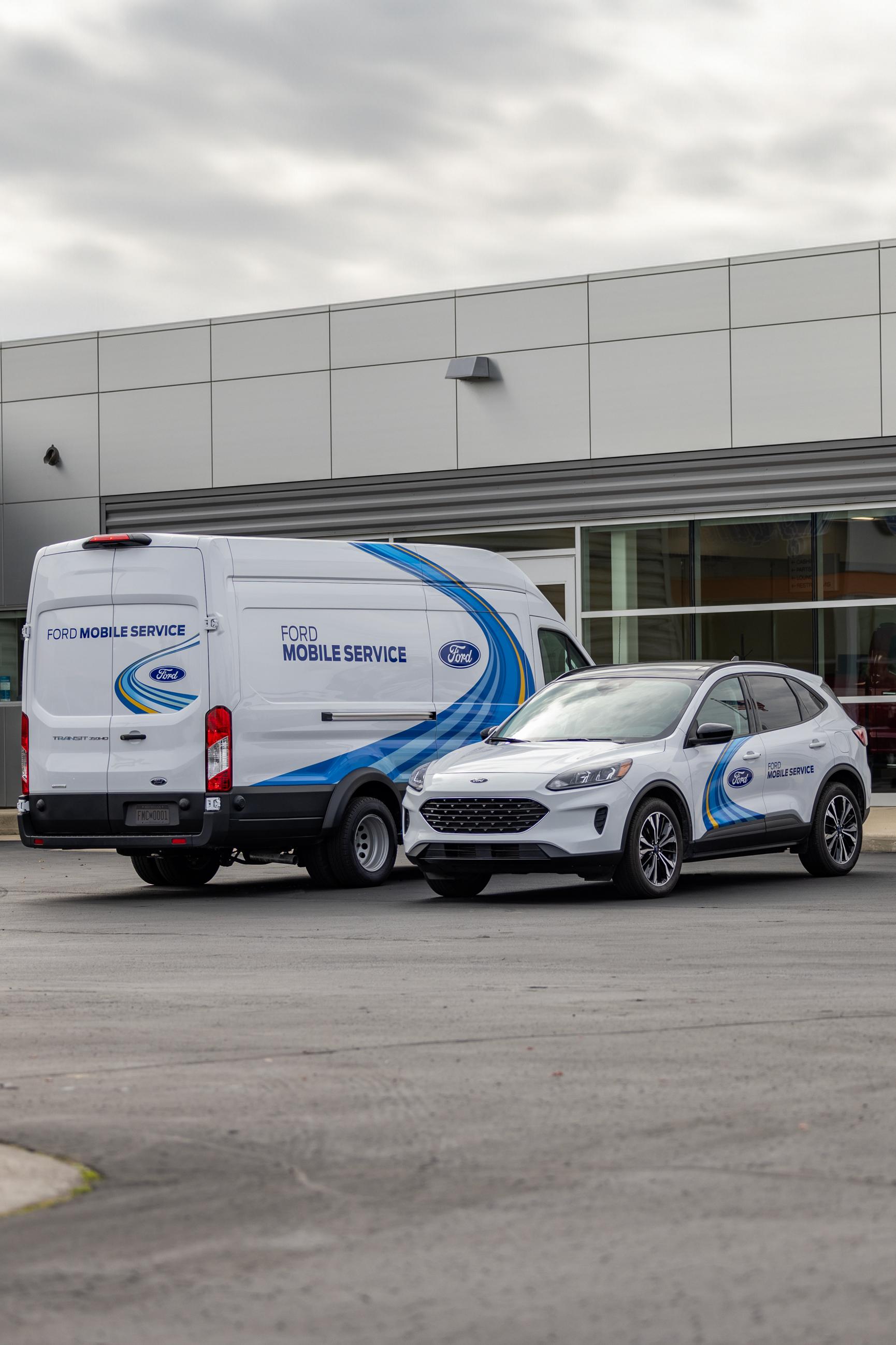 A white Ford van and a white 2025 Ford Escape each with Ford Mobile Service logo on them are parked next to each outside a dealership