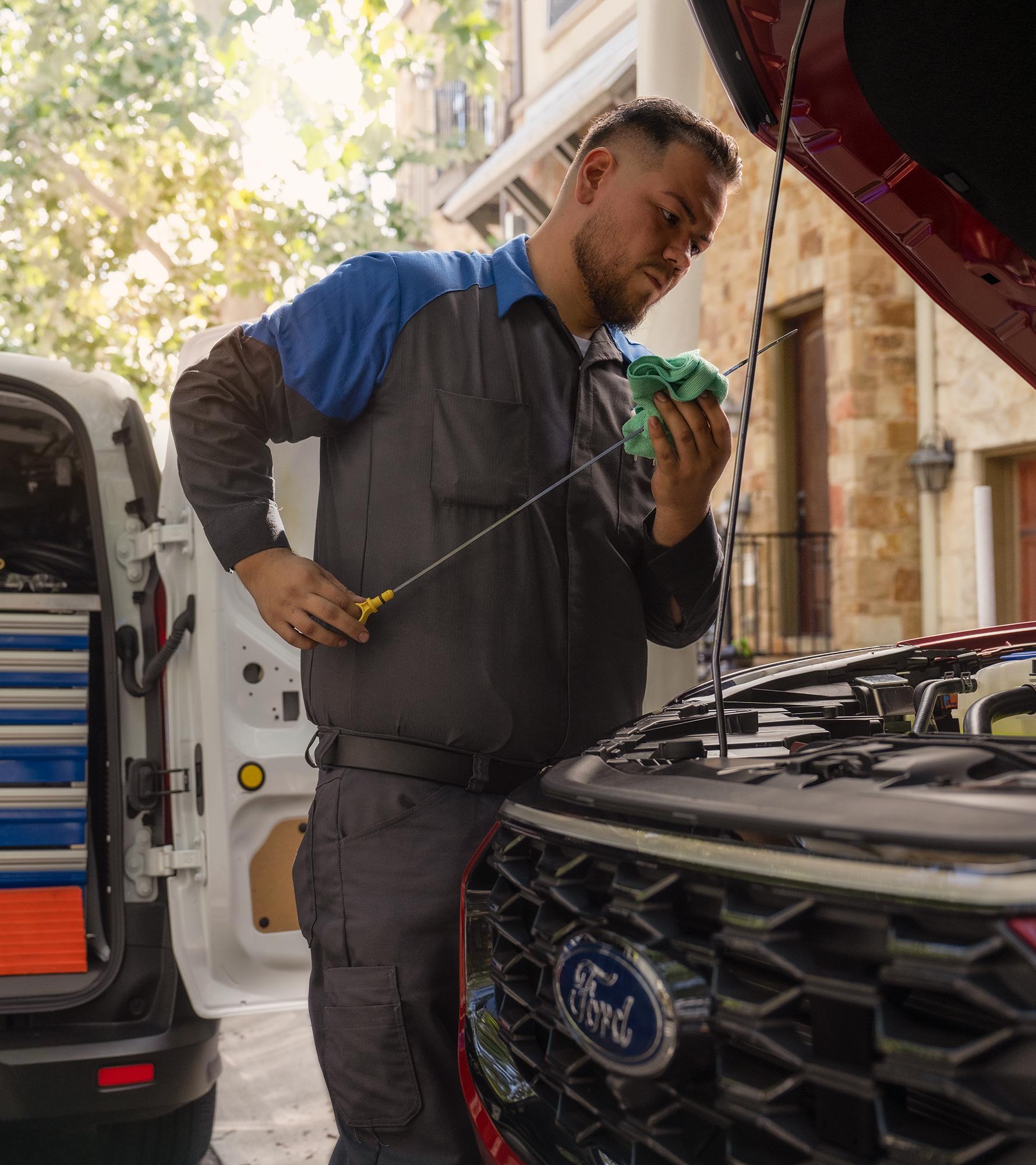 A Mobile Service vehicle technician checks a vehicle’s oil level on a dipstick