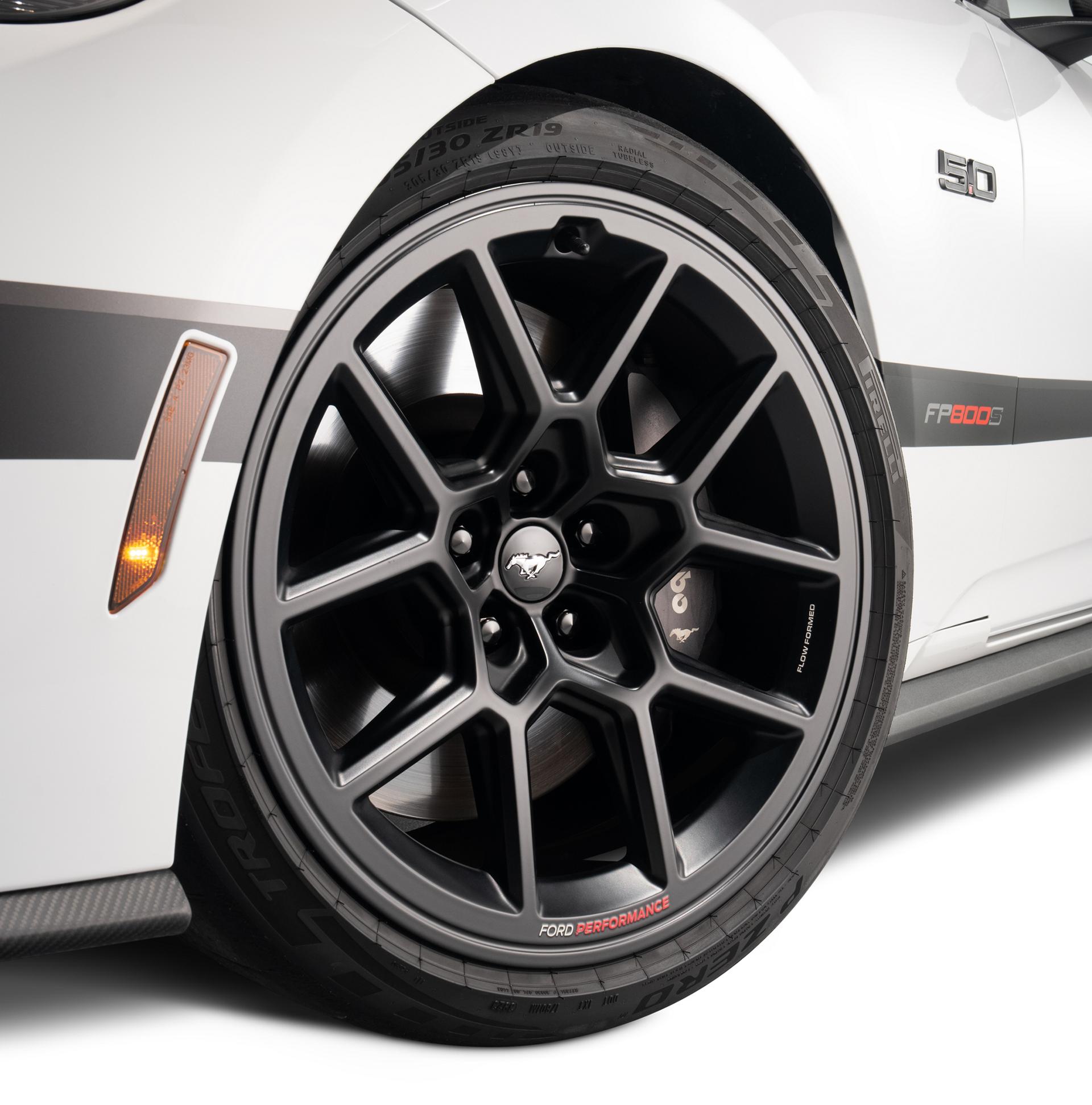 Close-up of the driver-side front black R1 wheel and lowered stance on the white Mustang