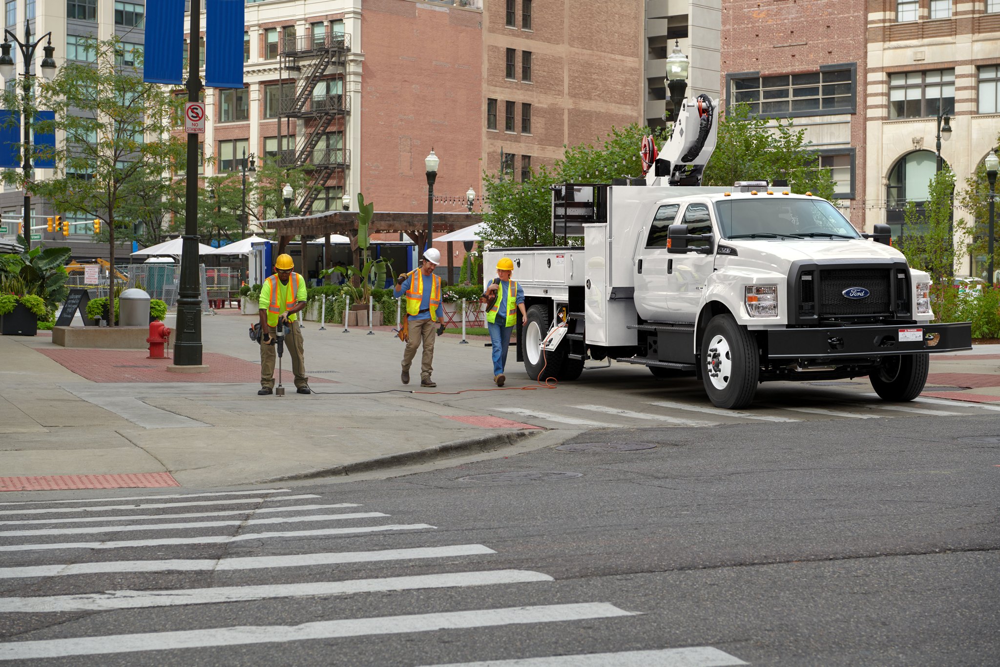 Workers walking near 2026 Ford F-750® Crew Cab in Oxford White with aerial lift upfit