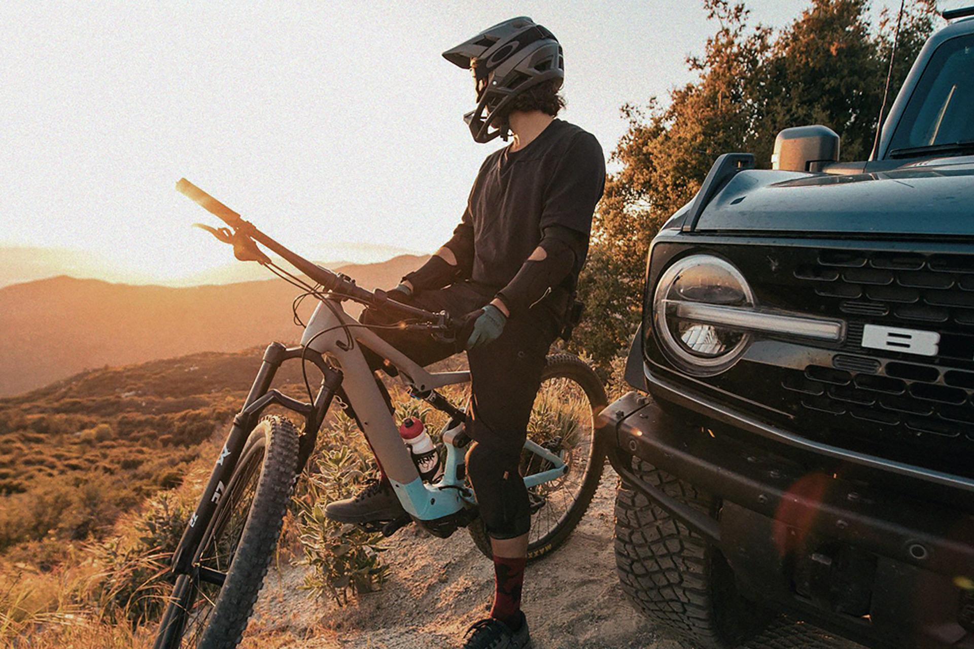 A person sitting astride a dirt bike in protective gear, next to a 2026 Ford Bronco® SUV