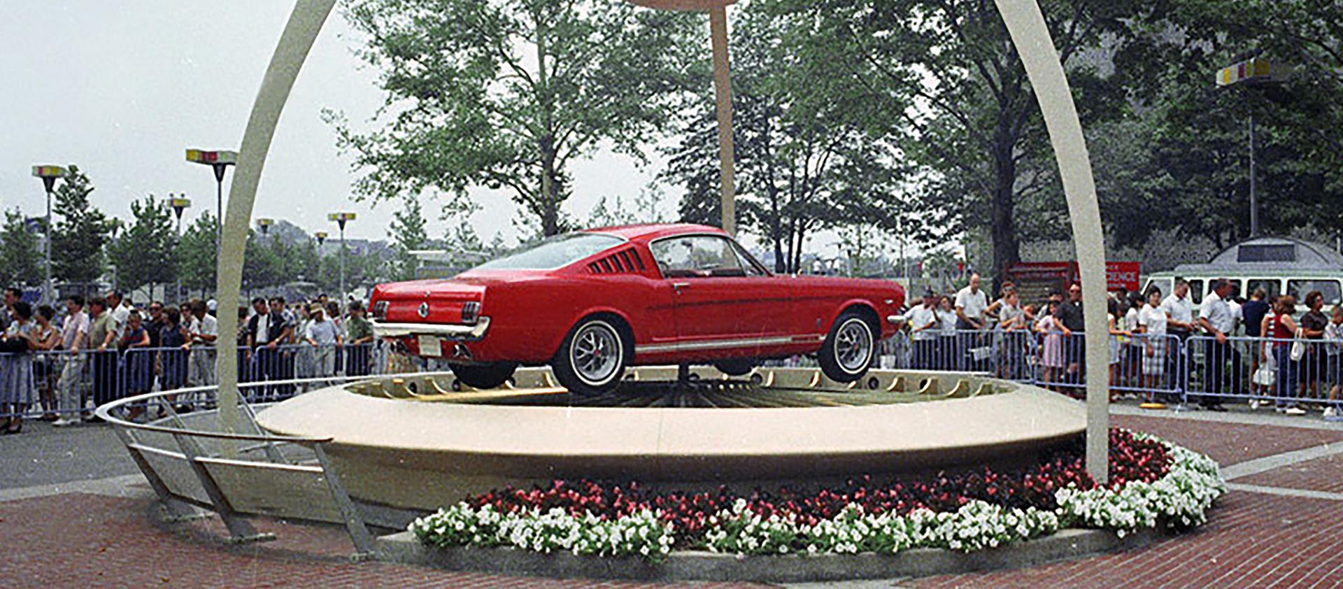 A red 1965 Ford Mustang car on a display platform