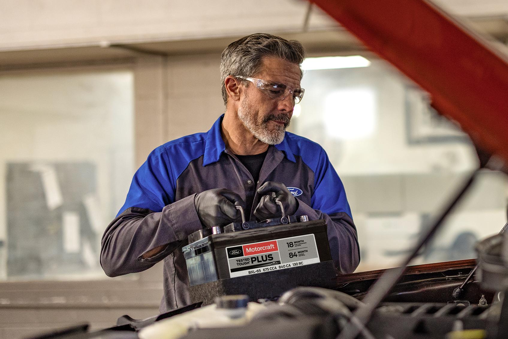 A Ford Service technician installs a new battery in a Ford vehicle