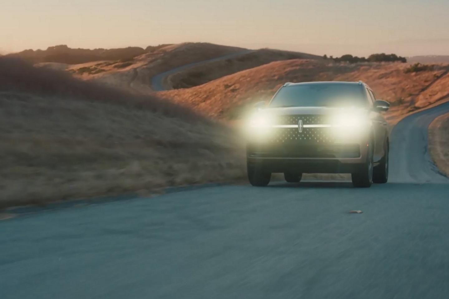 Una SUV Lincoln Navigator® 2025 se conduce al anochecer con los faros encendidos