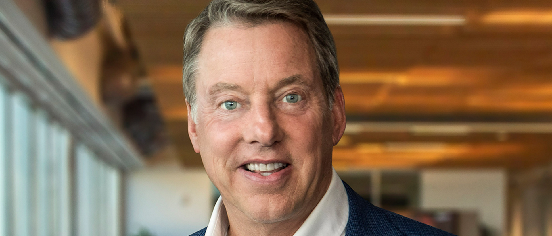 Bill Ford smiles candidly at camera in an open office space
