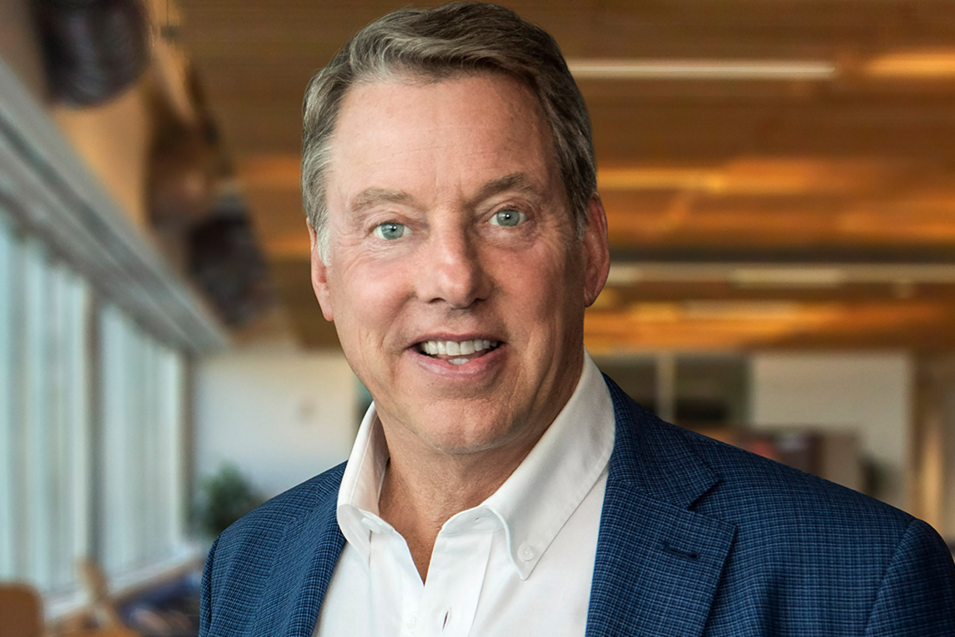 Bill Ford smiles candidly at camera in an open office space