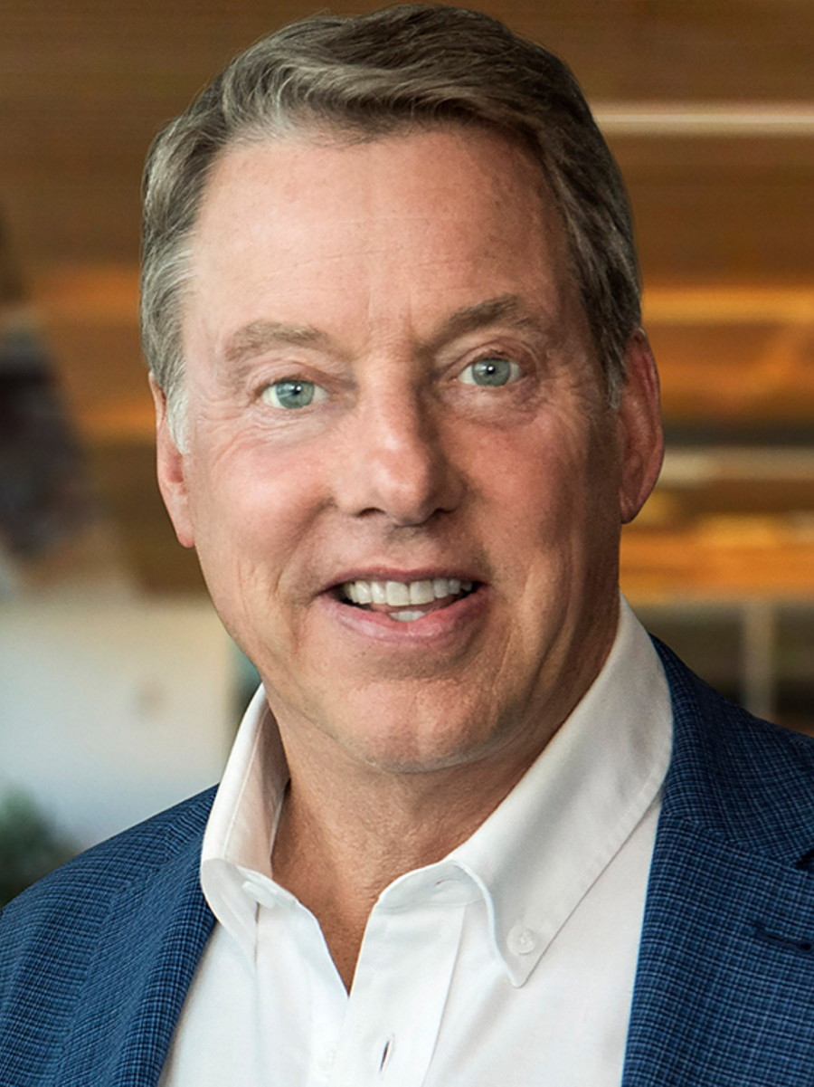 Bill Ford smiles candidly at camera in an open office space