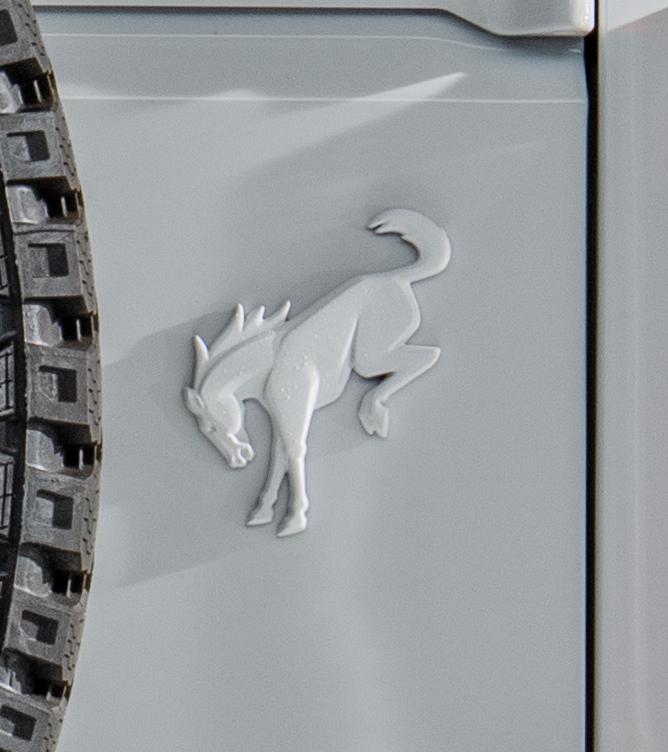 Close-up of the rear tailgate beside the spare tire showing the painted Bronco bucking horse badge.