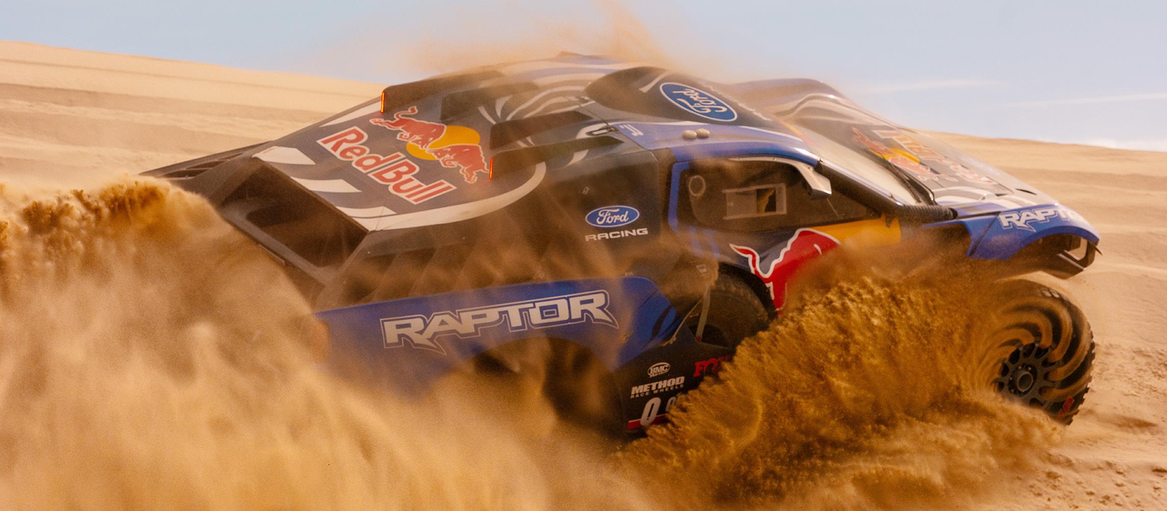 A competition Ford Raptor T1+ tearing through sand dunes