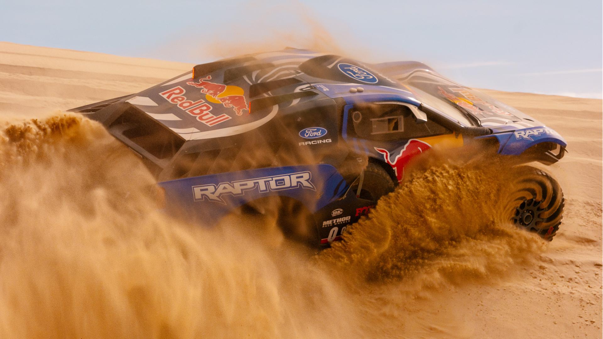 A competition Ford Raptor T1+ tearing through sand dunes