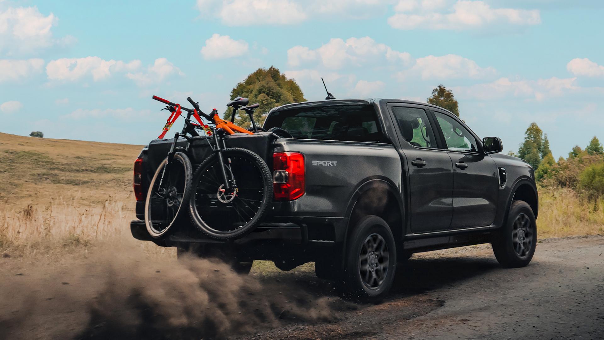 2026 Ford Ranger® truck driving on a dirt road with multiple bikes in the bed