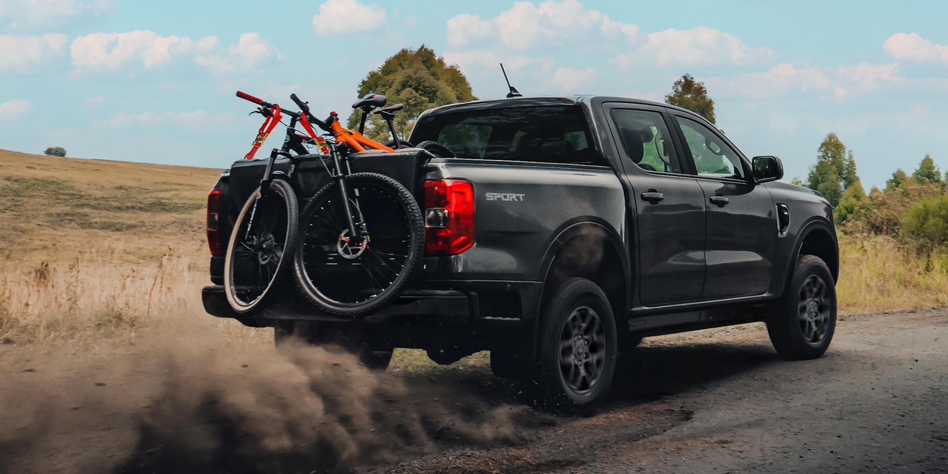 2026 Ford Ranger® truck driving on a dirt road with multiple bikes in the bed