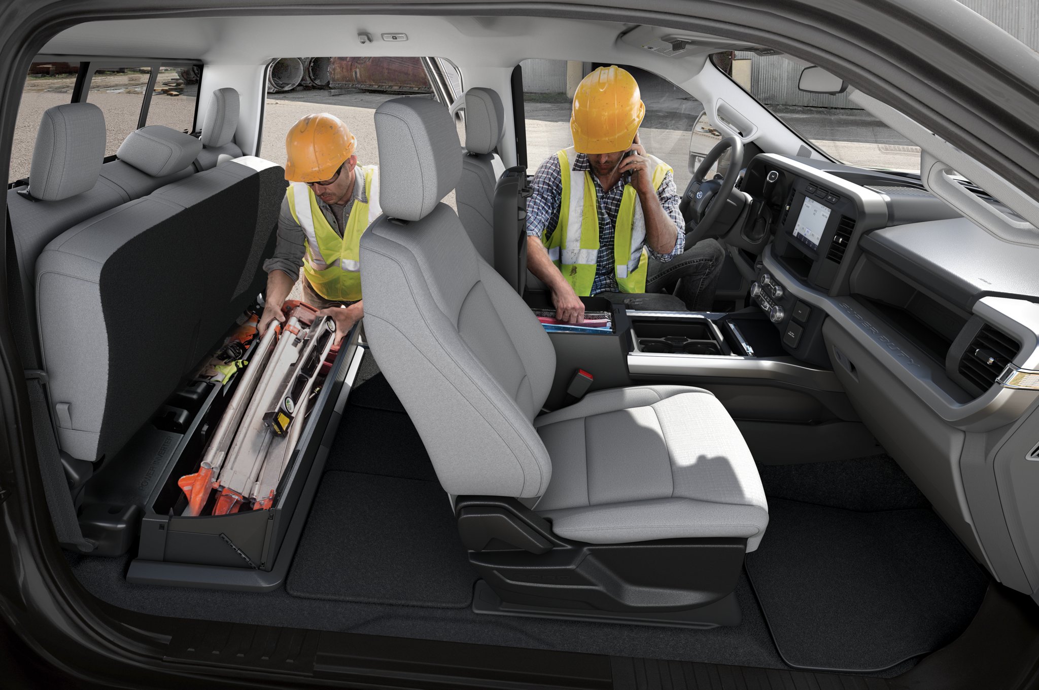 Two men in hard hats access the storage areas inside the cab of the 2025 Ford Super Duty® Chassis Cab