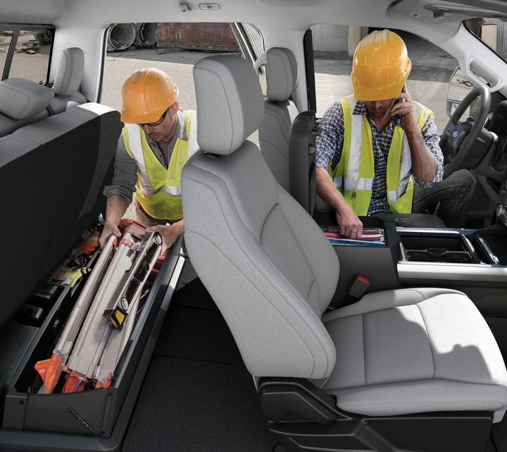Deux hommes portant un casque de sécurité accèdent aux aires de rangement à l’intérieur de la cabine du Ford Super Duty® à châssis-cabine 2025