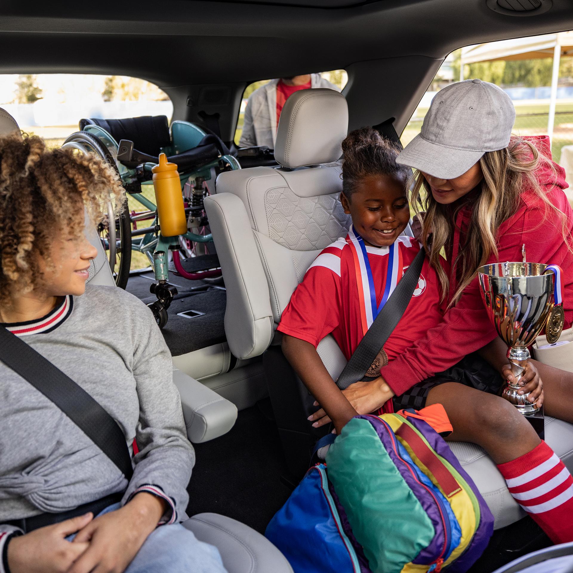 A parent helping secure youth soccer players in the second-row seats of a 2027 Ford Explorer® SUV