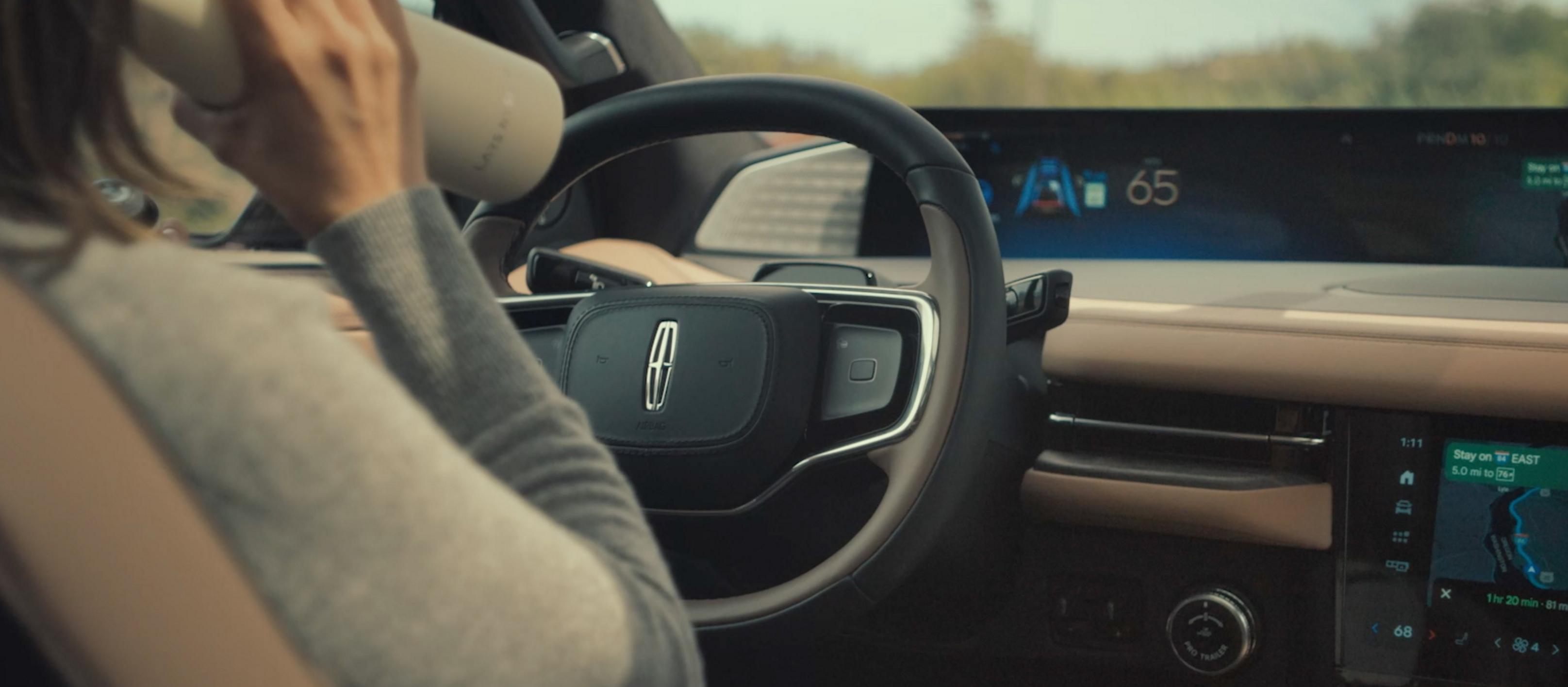 A woman drinks from a water bottle while driving a 2026 Lincoln Black Label Navigator hands-free