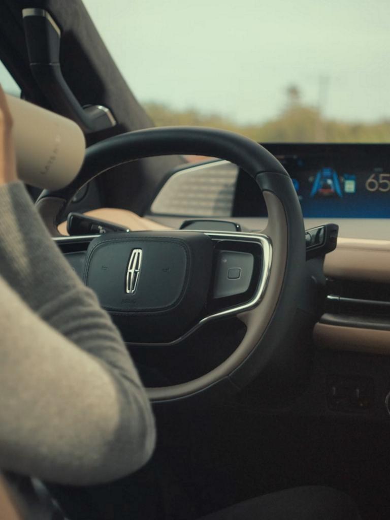 A woman drinks from a water bottle while driving a 2026 Lincoln Black Label Navigator hands-free