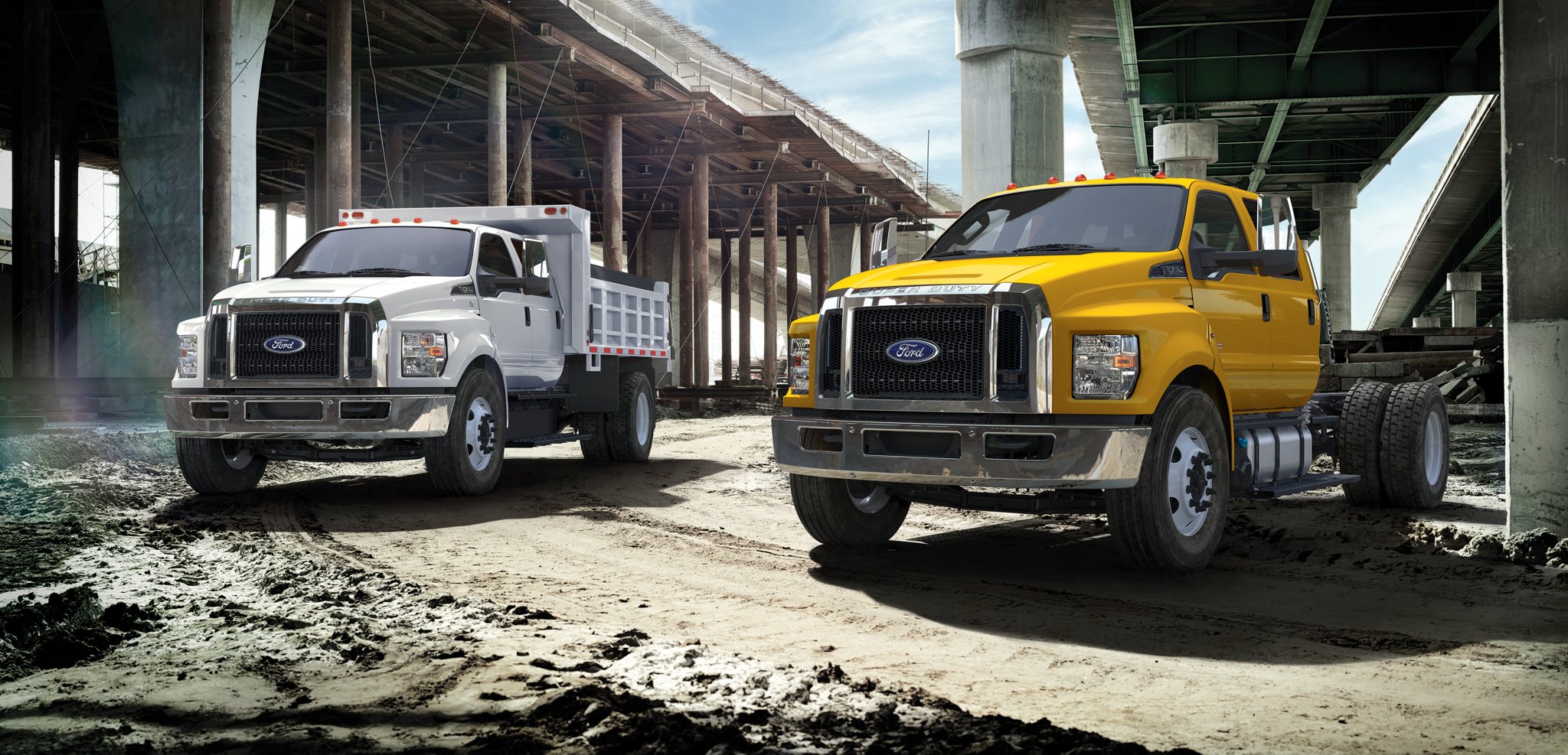 2026 Ford F-750® models with dump truck upfits parked alongside one another near an overpass