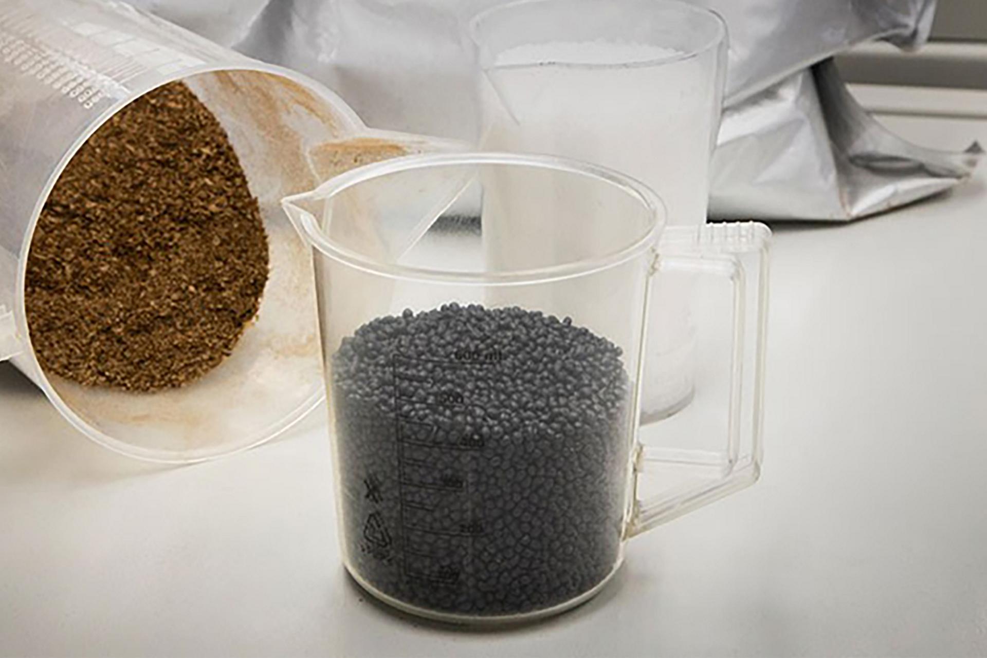 Two measuring cups on a lab table, one full of coffee beans and another full of coffee chaff