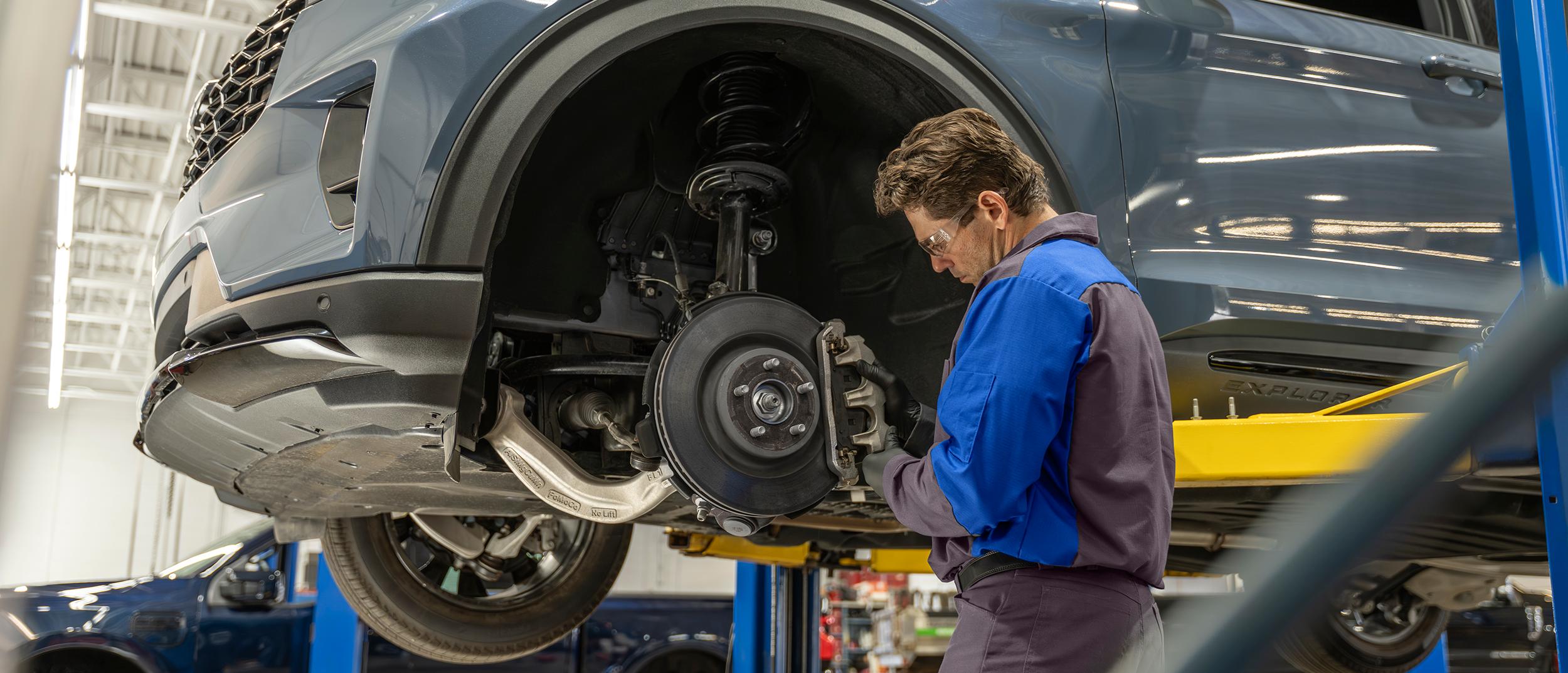 A Ford Service technician inspects the brakes and rotors on a Ford vehicle