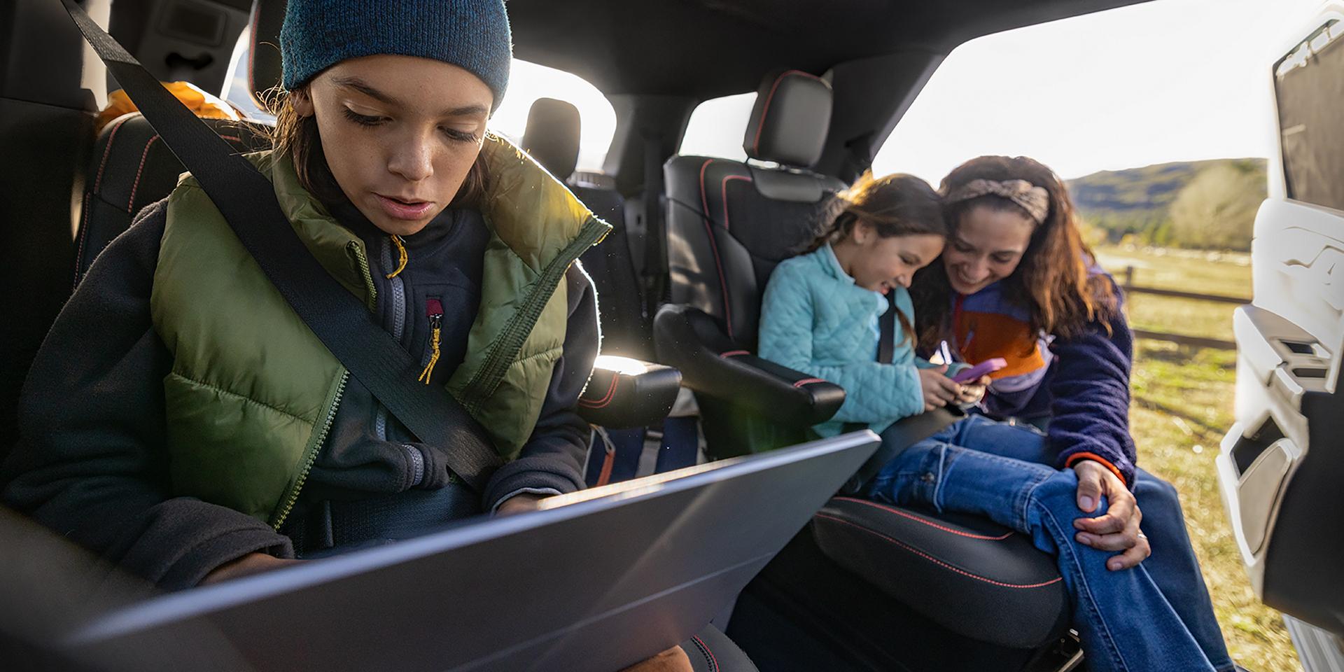Two children using connected devices in the second-row seats of a 2027 Ford Explorer® SUV